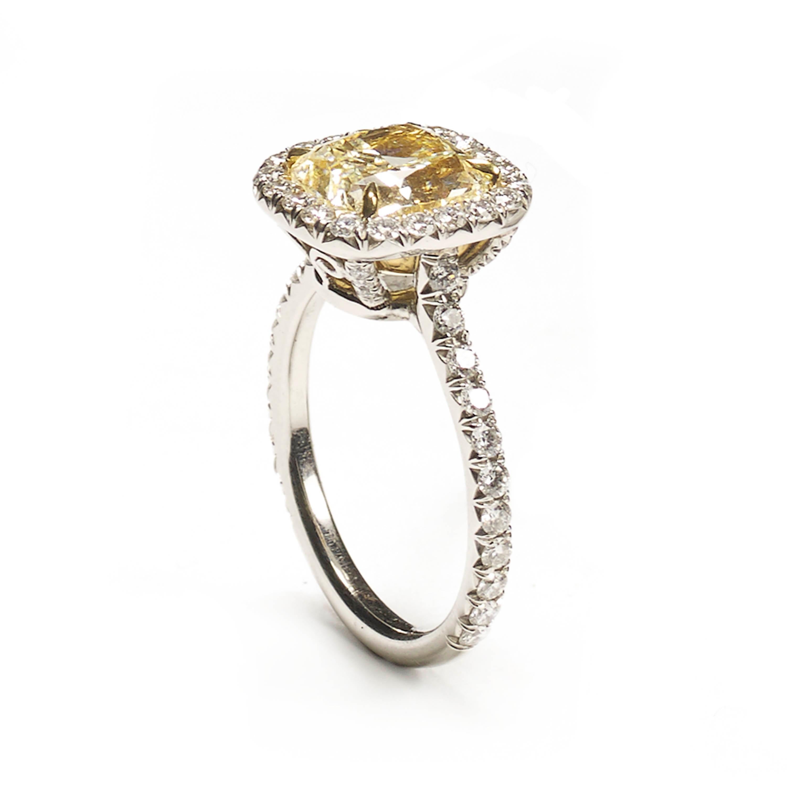 A modern micro pavé yellow diamond ring, set with an approximately 3.00ct cushion-cut light yellow diamond, in a yellow gold, four claw setting, with a micro pavé set surround, shoulders and bezel, with 54 round brilliant-cut diamonds, with a total