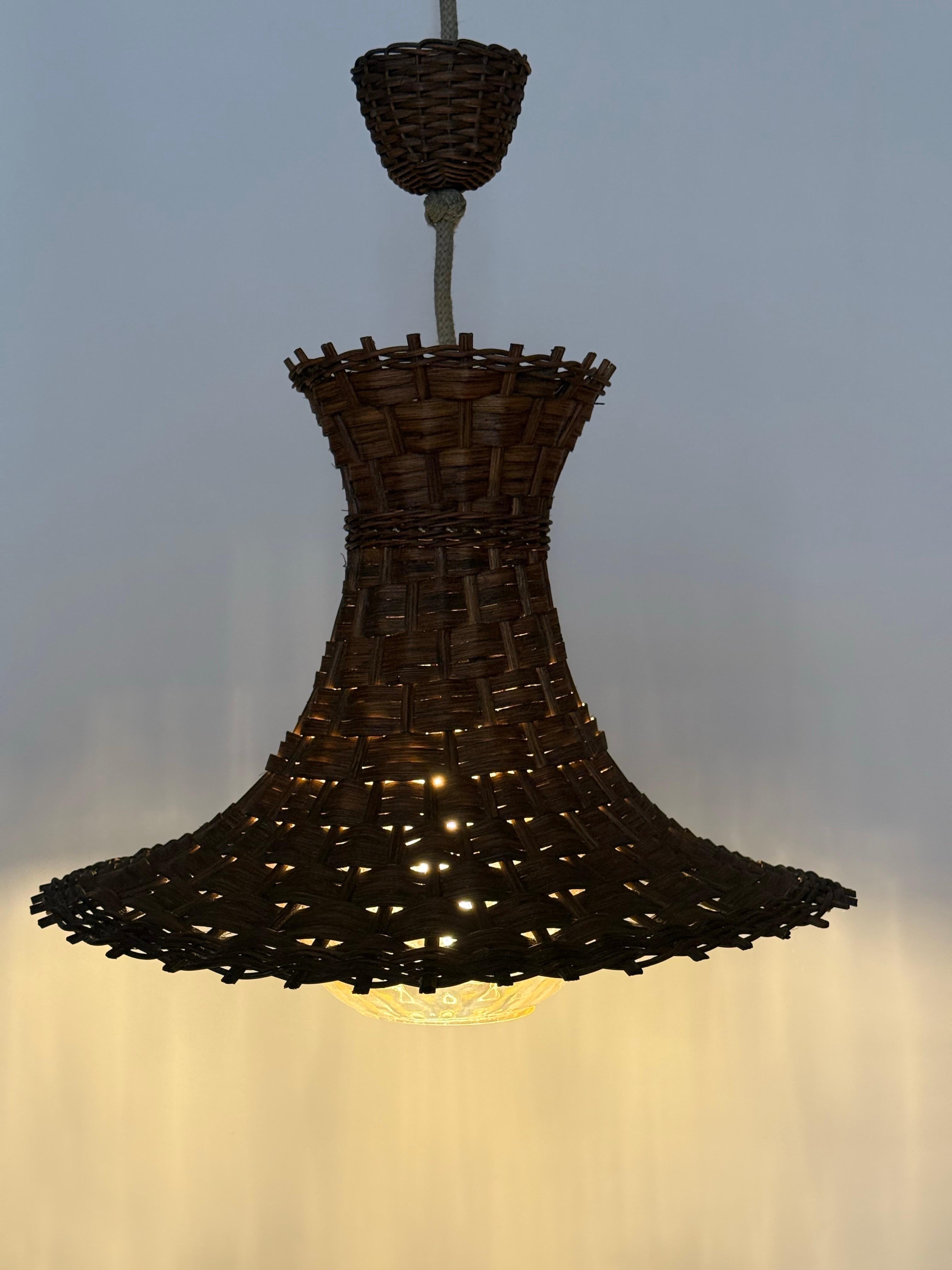 Esta hermosa lámpara colgante, fabricada en Alemania por la renombrada empresa Peil & Putzler, es una auténtica obra de arte. La pantalla, cuidadosamente tejida a mano con madera y sauce, encarna la artesanía tradicional y el diseño moderno. En el