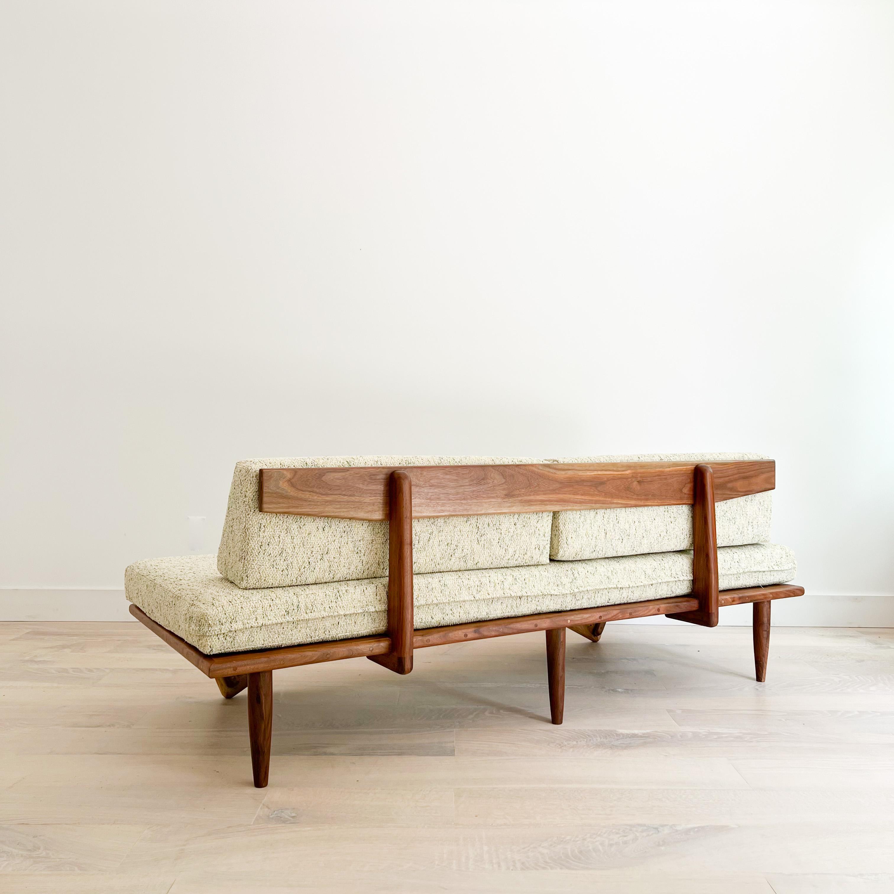 One of our early atomic sofas made in 2016 by our in house craftspeople. This platform sofa features a sculpted solid walnut frame with boomerang legs and a structurally sound back support. The walnut frame has been sanded and oiled nicely so that