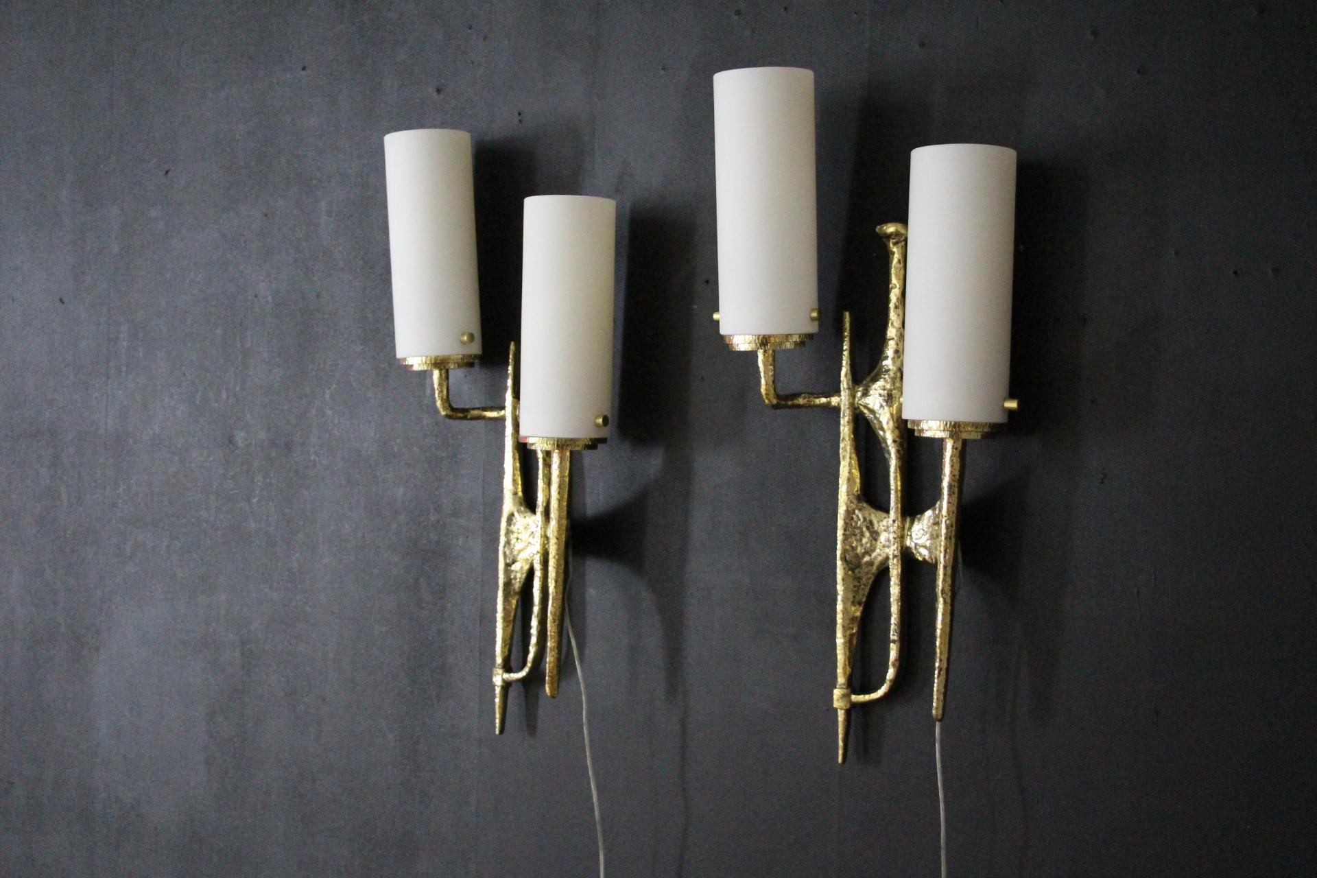 This spectacular and dramatic pair or brutalist bronze sconces is in the style of Maison Arlus in the manner of Felix Agostini.
This pair of wall lights is in gilded bronze . It is inspired by tree bark and its branches thanks to A very special
