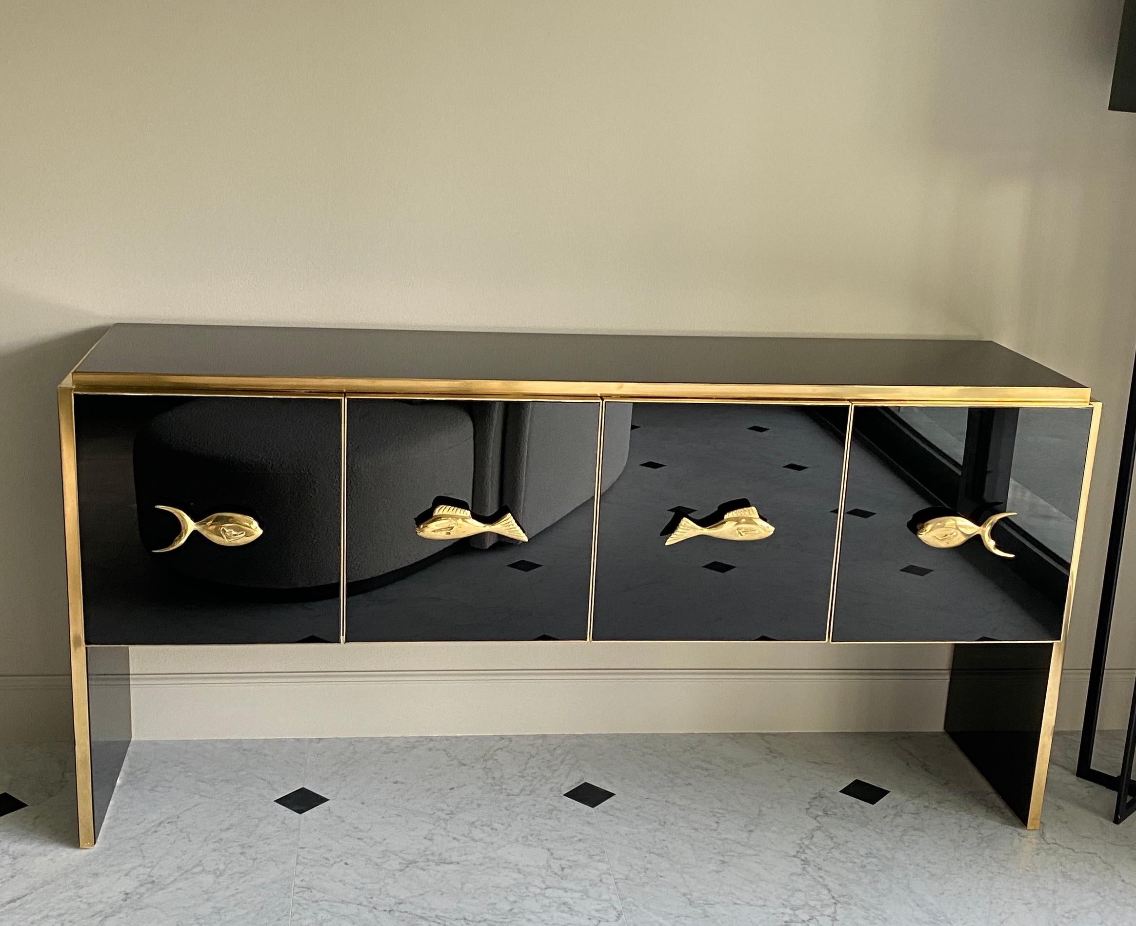 Very fine handmade sideboard  by a master artisan. Brass frame with handmade and hand-cut black glass , four doors with fish shaped brass handles. 

 
