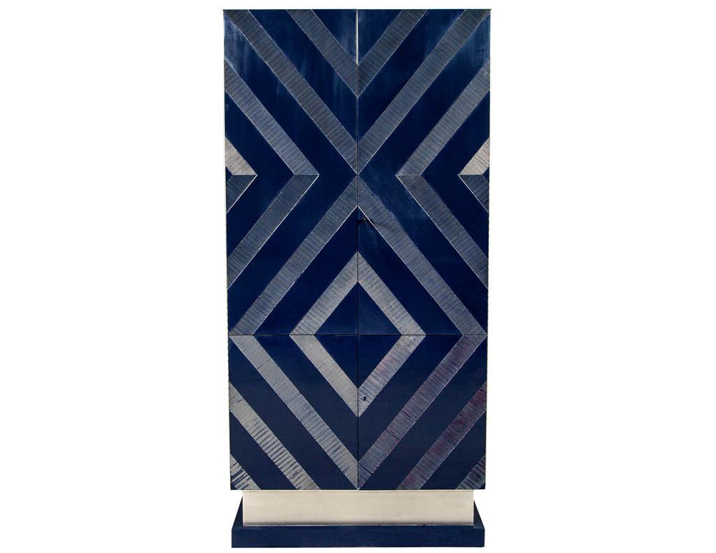 Modern midnight blue bar cabinet. Design with a Classic ribbed diamond pattern design on the doors. This tall cabinet opens into a bar with a drop down shelf for mixing. Glass shelves and interior light with mirrored back. This cabinet is finished