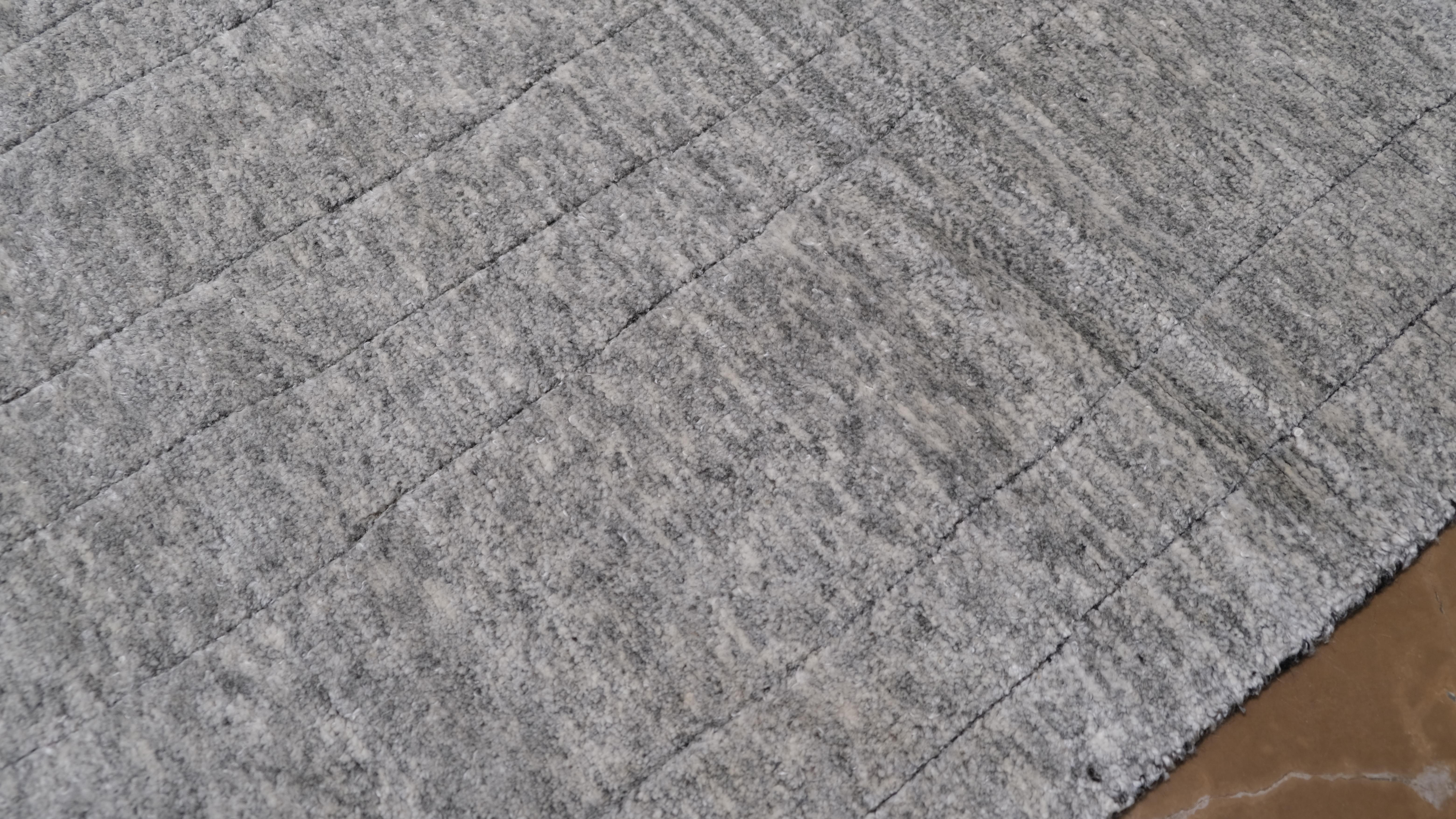 Eleganza raffinata per questo tappeto in lana annodato a mano, caratterizzato da un design geometrico moderno e minimalista. La sottile disposizione dei motivi lineari in varie tonalità di grigio crea un senso di profondità e raffinatezza, pur