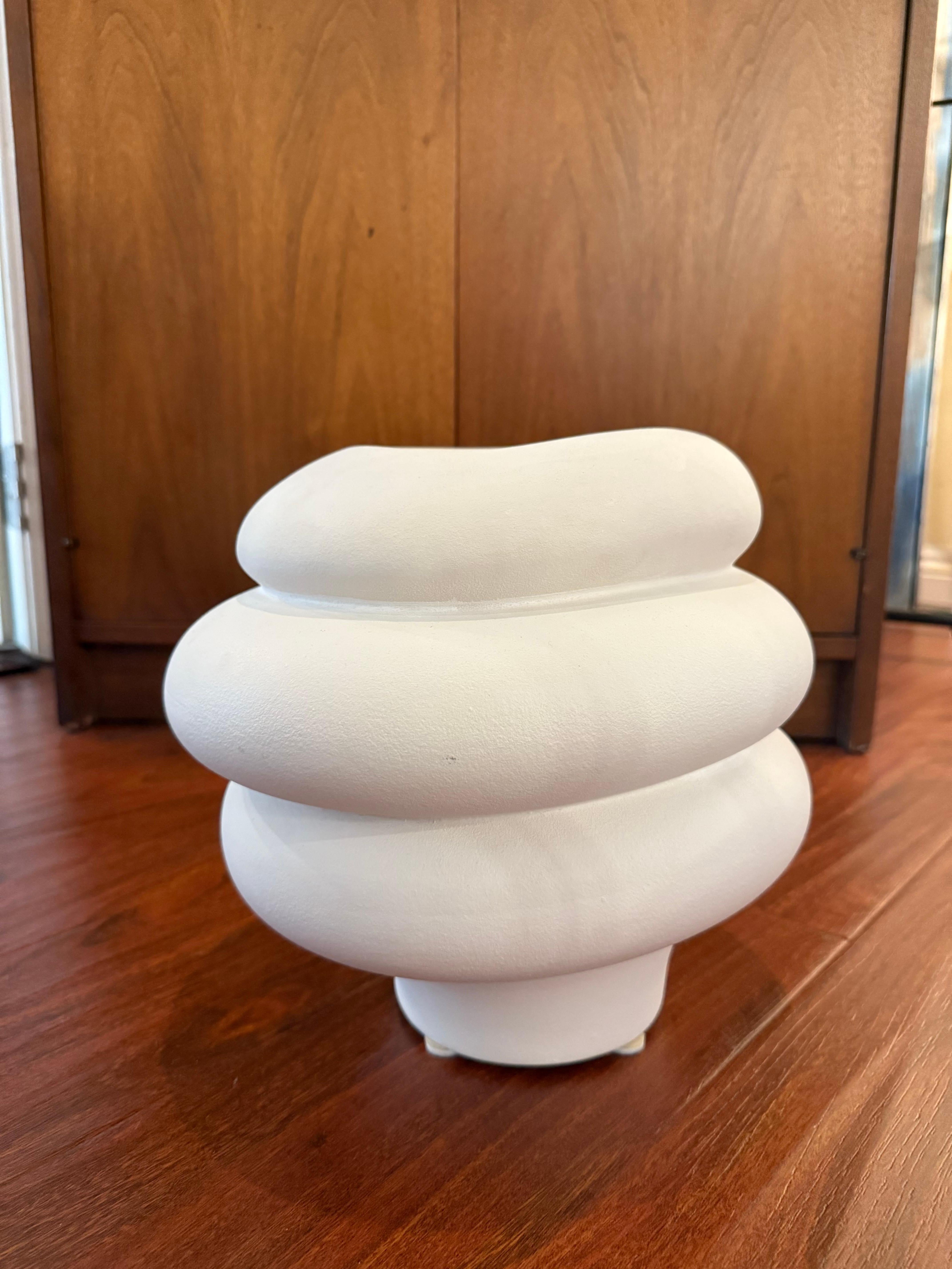 This postmodern sculptural ceramic vase features a fluid, organic spiral silhouette in matte cream. Evoking the playful geometry of Memphis-era design while retaining a minimalist elegance, it is a classic representation of 1980s postmodern design.