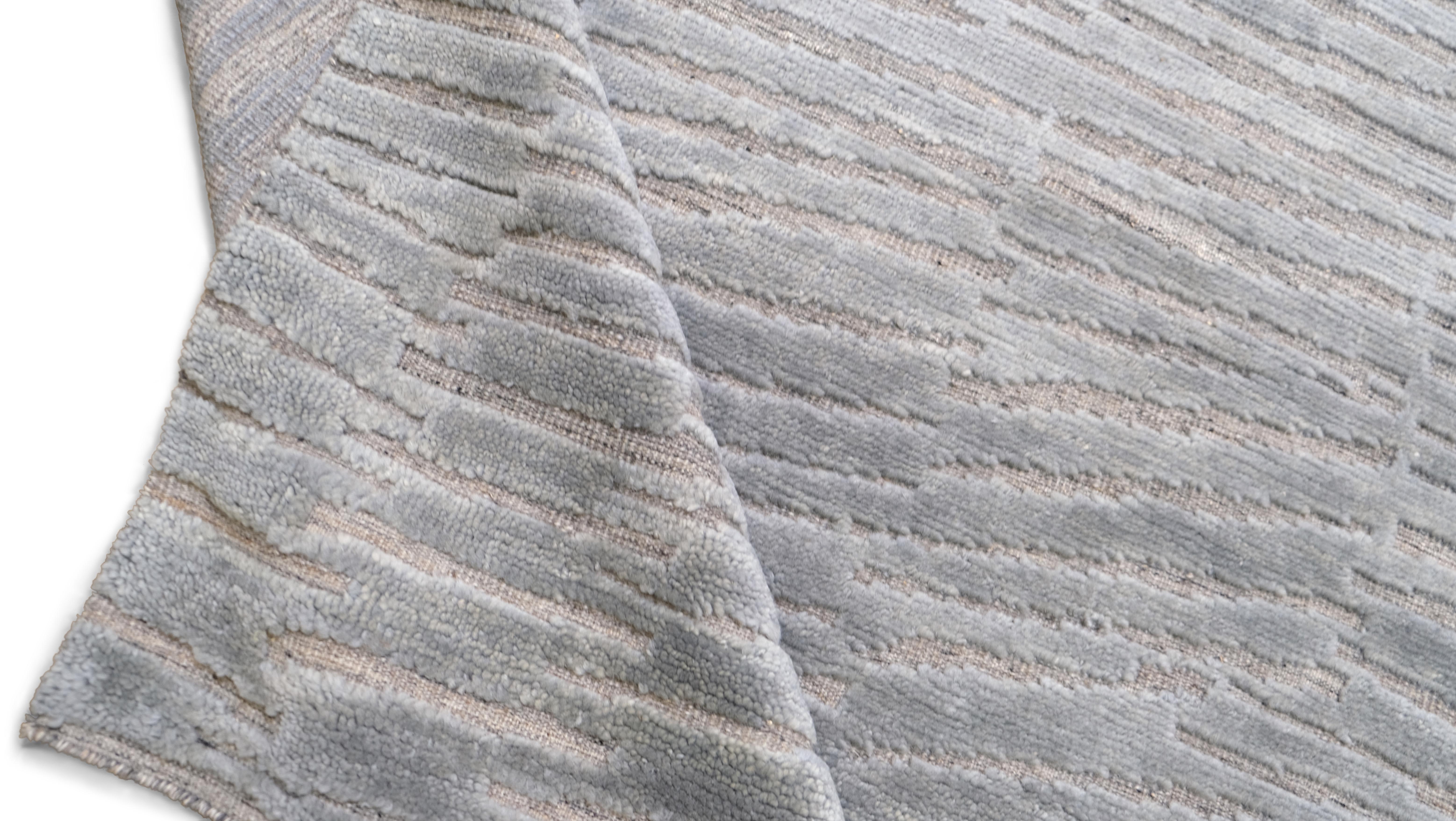 Dieser moderne, handgeknüpfte Wollteppich wertet Ihren Raum durch seine schlichte Raffinesse auf. Mit seinem raffinierten, strukturierten Design strahlt dieser Teppich eine subtile Eleganz aus, die ihn zu einem vielseitigen Mittelpunkt für