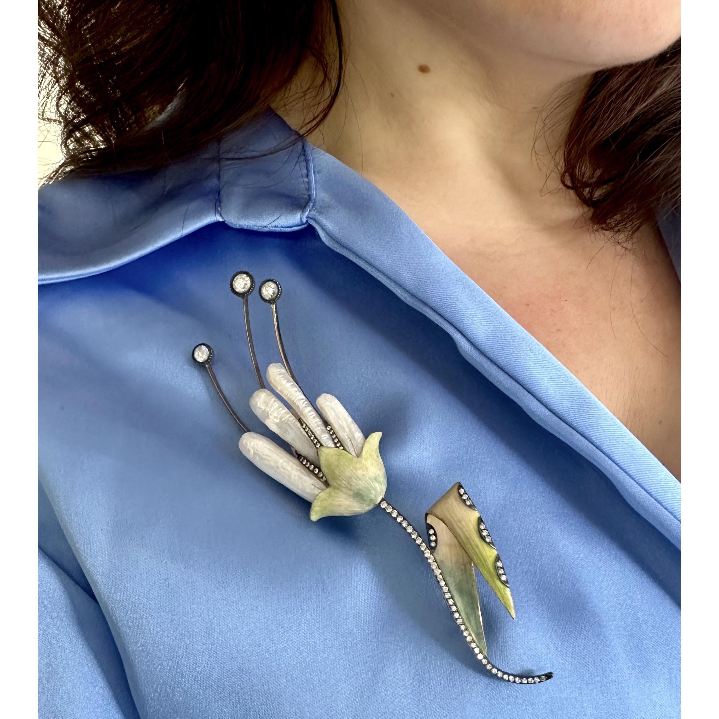 Broche florale moderne en perles du Mississippi, diamants et émail, avec trois anthères serties de diamants taillés en rose, des pétales en perles du Mississippi, une feuille et un sépale en émail vert nuancé avec une tige sertie de diamants ronds