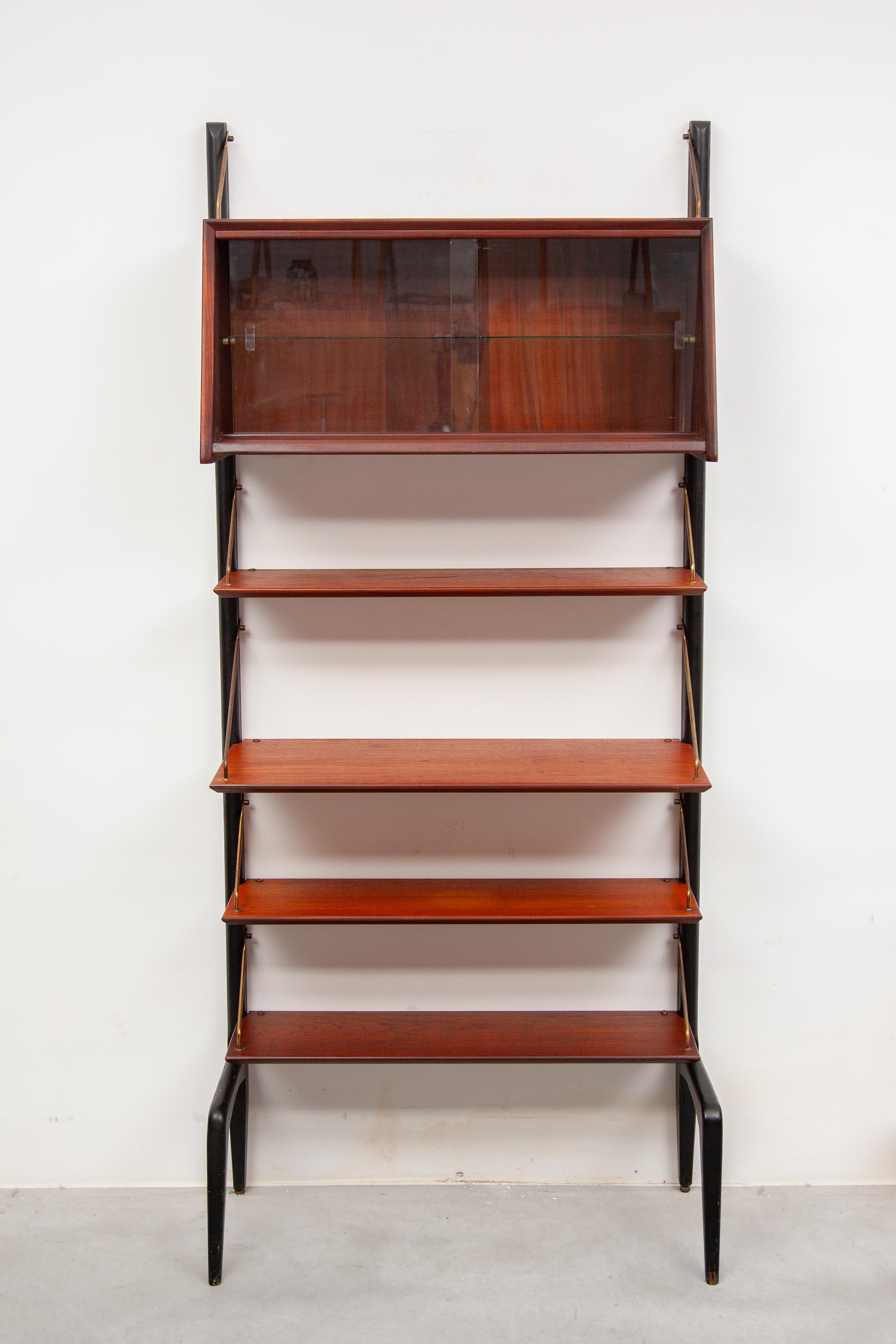 Modern modular teak wall unit designed by Louis van Teeffelen for Webe, circa 1960. Black lacquered wooden uprights with ant legs. Multiple teak wooden shelves with brass hang system and one hanging display cabinet with glass doors. In very good