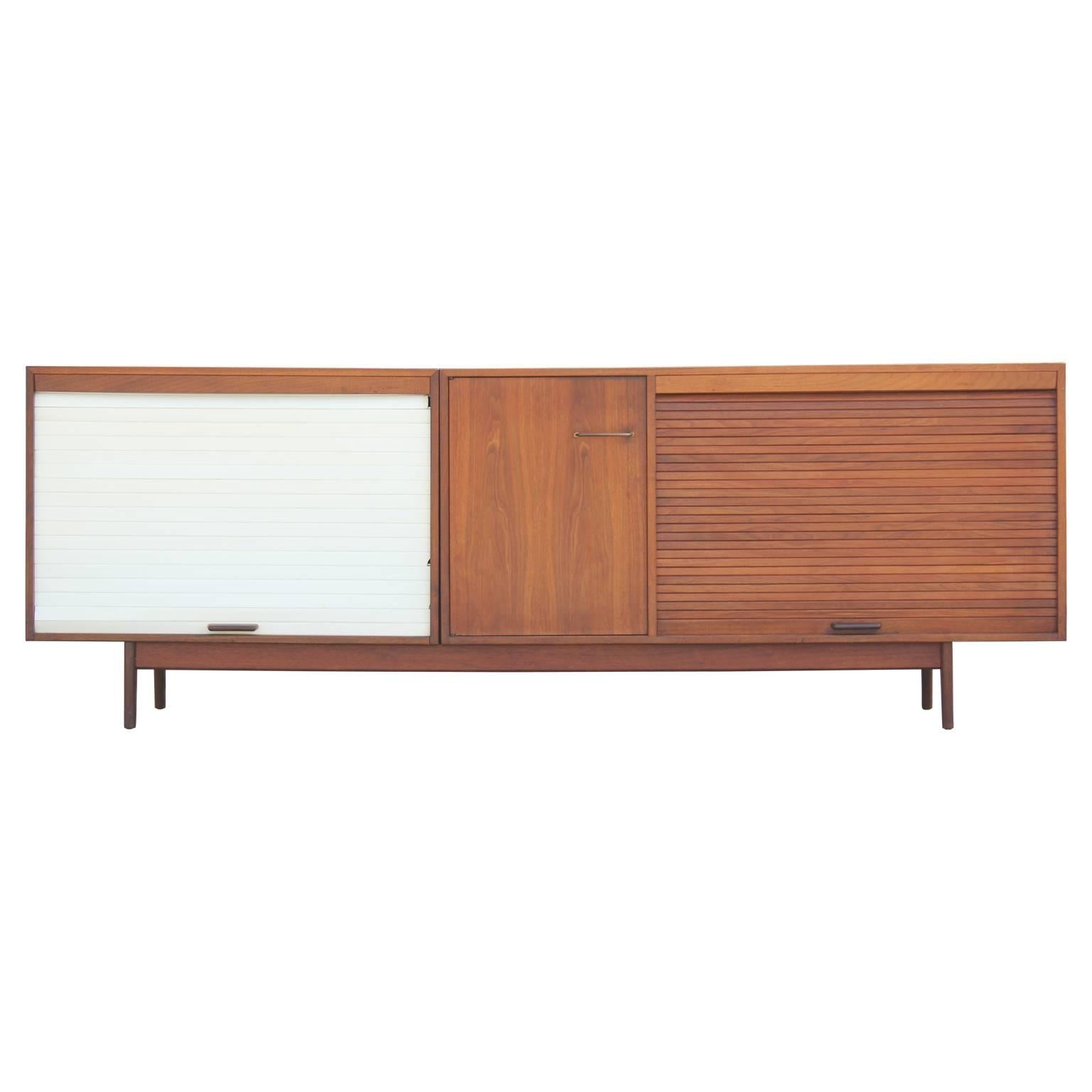 Gorgeous modern walnut sideboard or credenza with one white plastic tambour door and one made from walnut. There are a few chips in the plastic and the piece would like nice refinished, but an overall great credenza. 