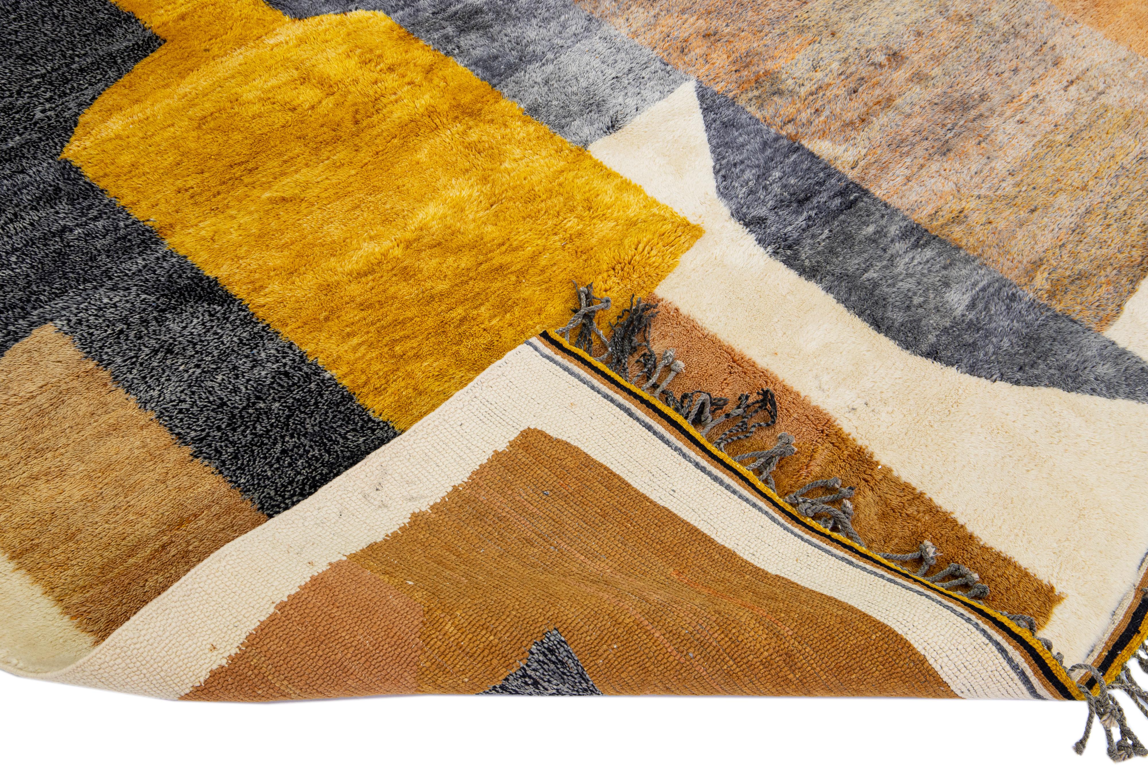 Preciosa alfombra marroquí de lana anudada a mano con campo beige. Esta alfombra moderna tiene acentos grises, marrones y amarillos en un precioso diseño abstracto con flecos grises.

Esta alfombra mide 8'3