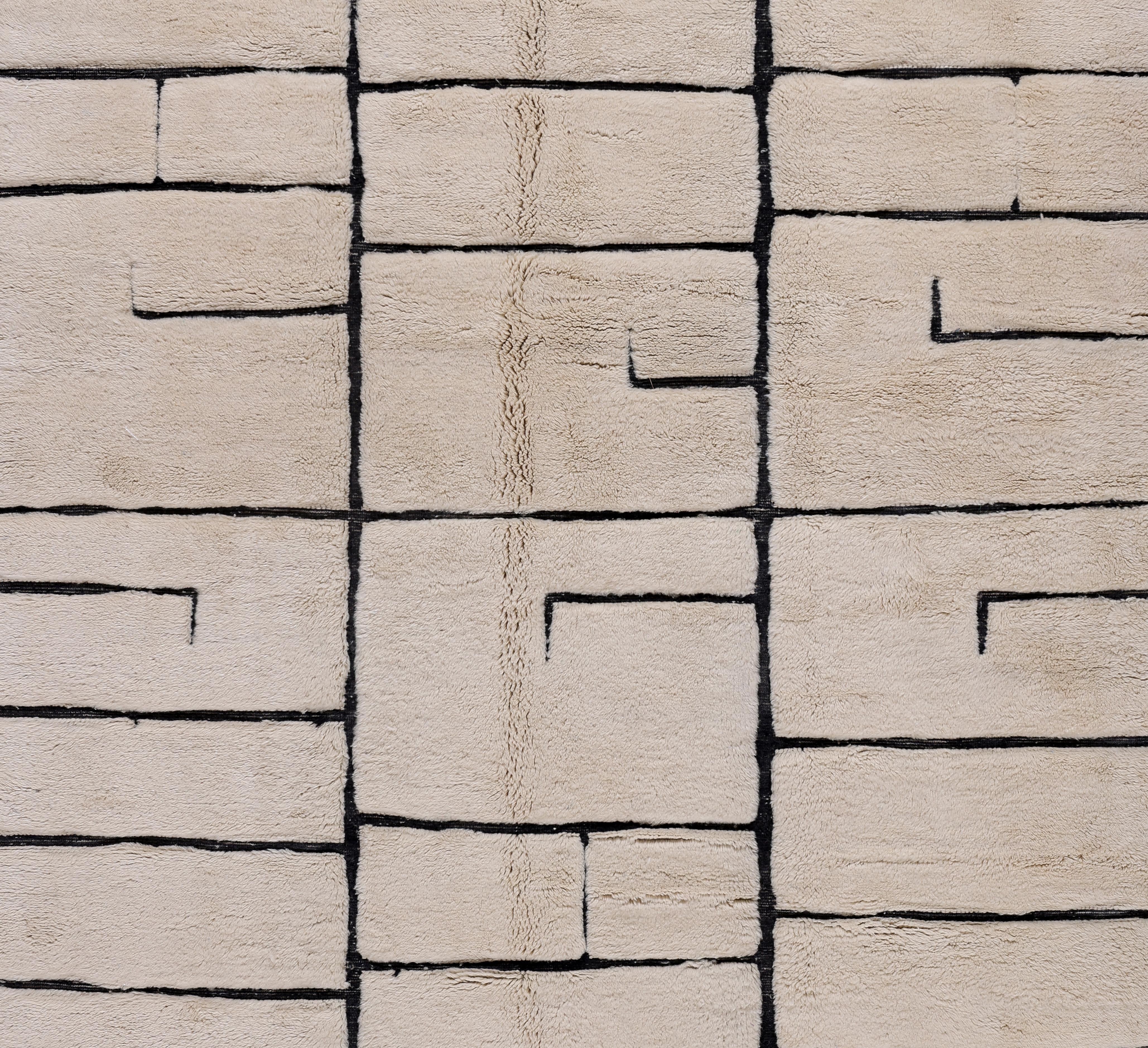 Questo tappeto marocchino contemporaneo Beni Mrirt fonde un design audace con un'antica maestria artigianale, con un motivo geometrico a blocchi strutturato in lana avorio delineato da bordi neri. Ogni forma sembra un elemento architettonico e