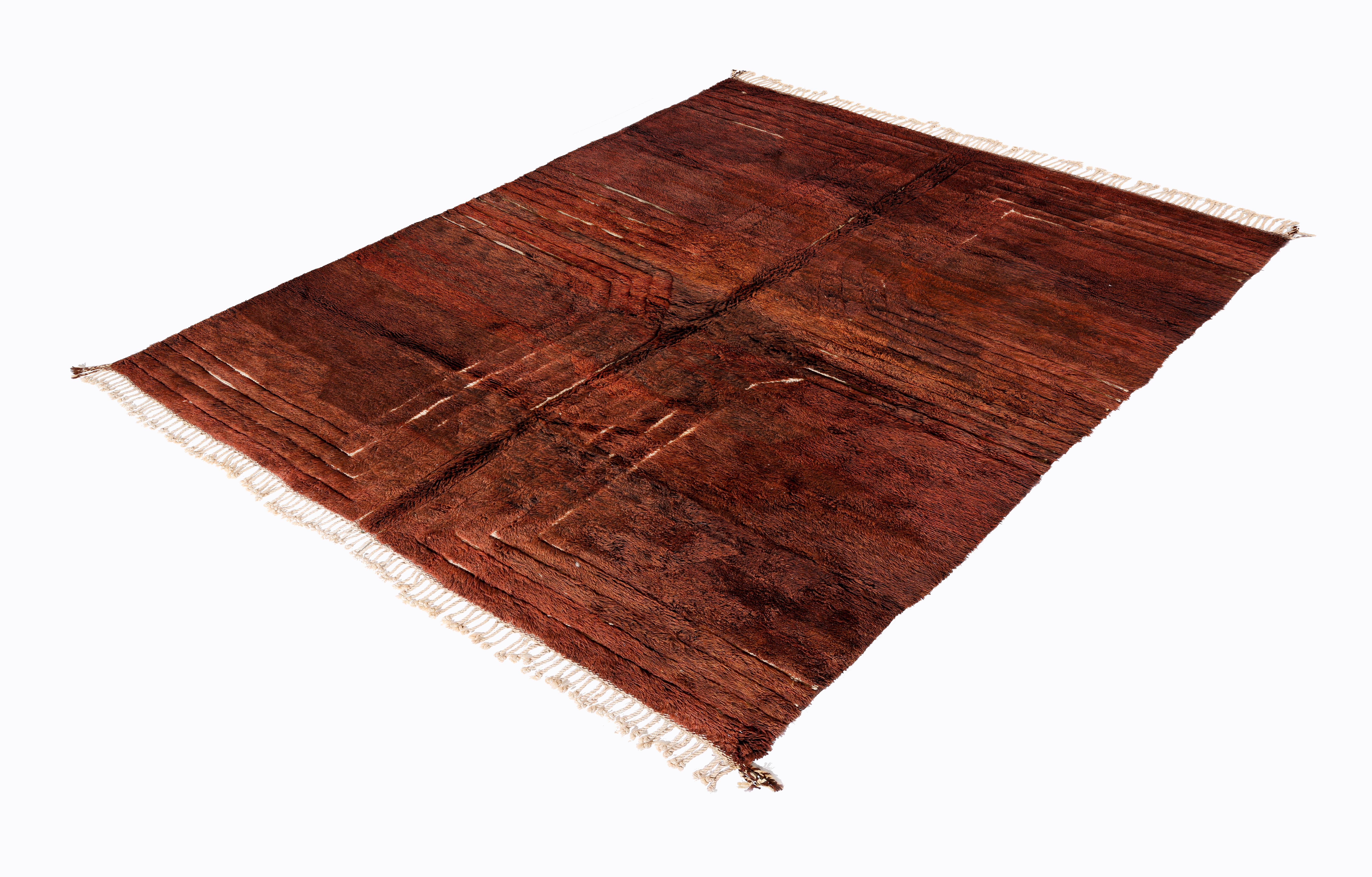 Questo splendido tappeto marocchino Beni Mrirt, annodato a mano, presenta un'estetica audace e terrena con un ricco campo di lana color terracotta e rosso-marrone, accentuato da sottili trame lineari che formano una composizione a griglia