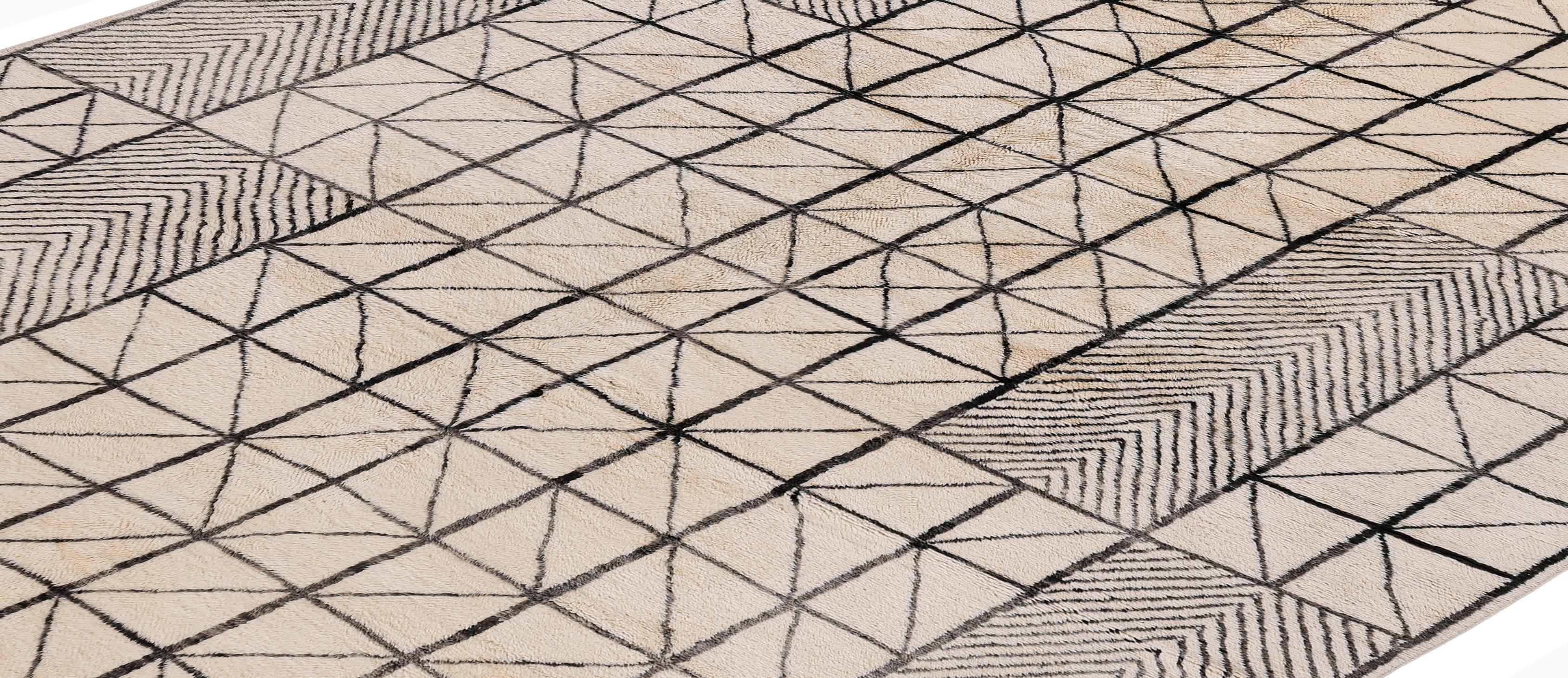Esta alfombra marroquí Beni Ourain, hecha a mano, presenta un llamativo y moderno diseño de rejilla realizado con lana natural anudada a mano en marfil y negro intenso. La alternancia de paneles triangulares y chevron crea un ritmo arquitectónico
