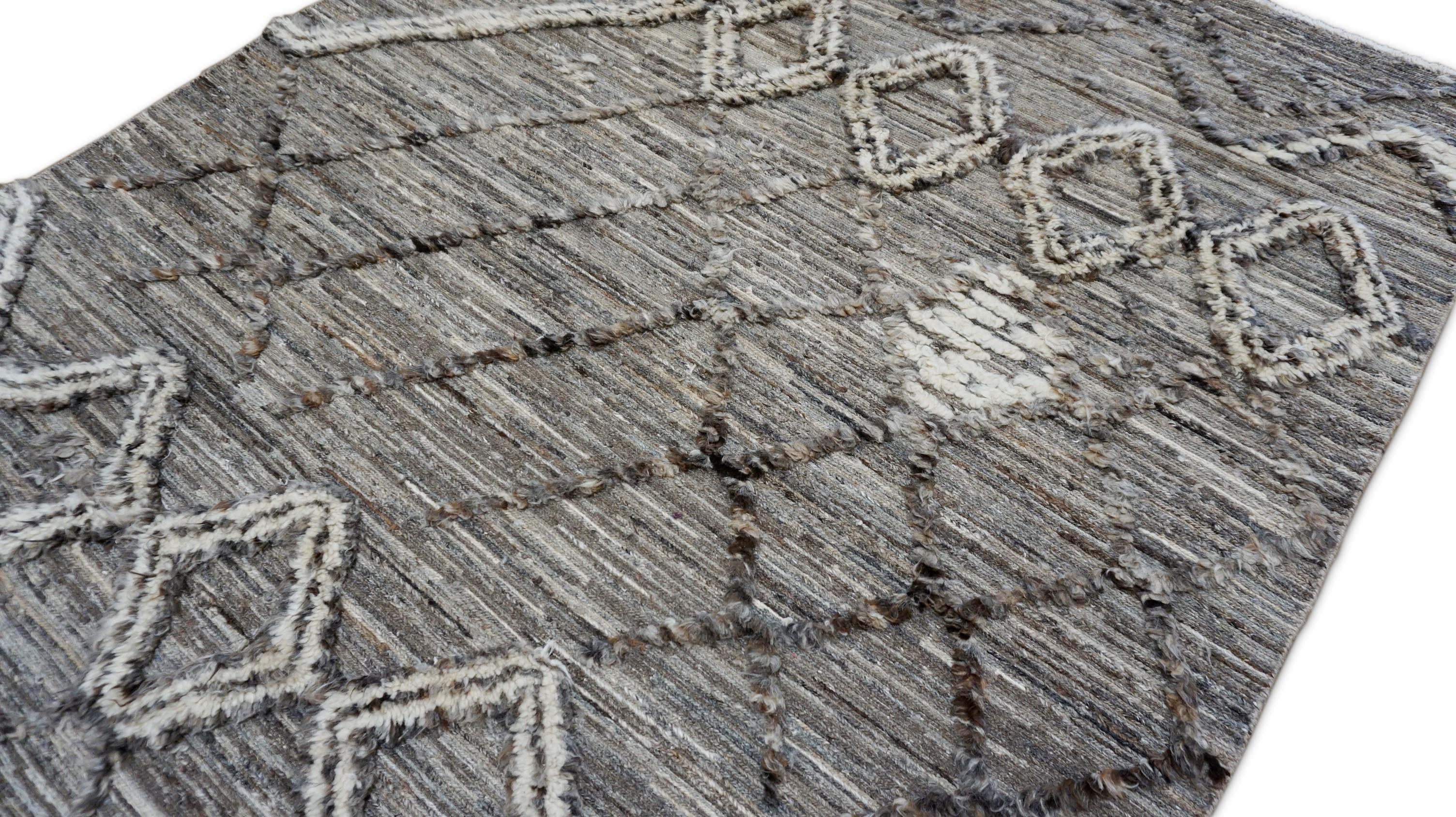 Esta alfombra contemporánea de lana anudada a mano presenta un atrevido diseño de inspiración tribal, que mezcla texturas rústicas con geometría moderna. Sobre un fondo marrón grisáceo moteado, los motivos lineales en marfil y carbón -que incluyen