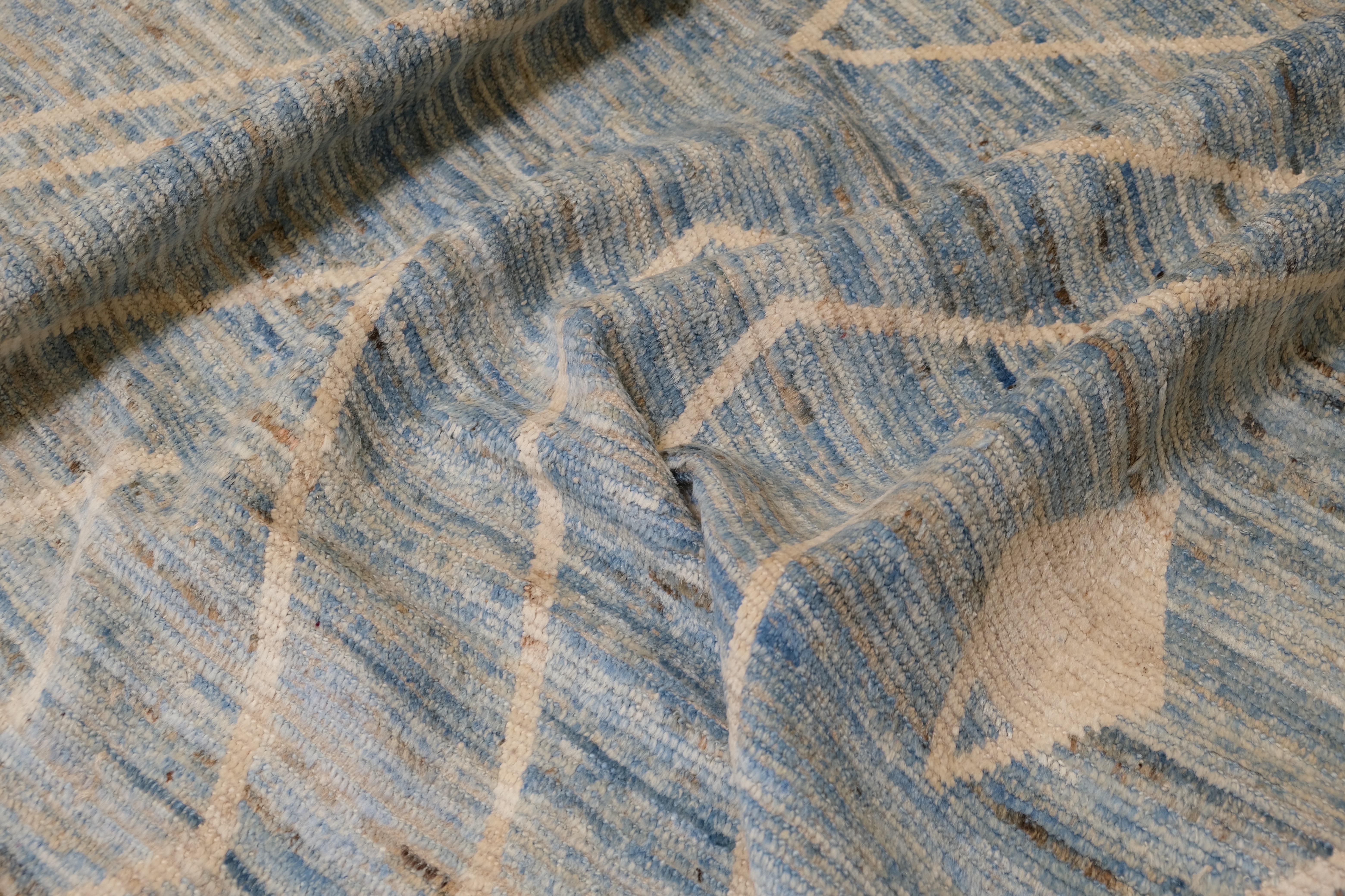 Elevate your home with this stunning hand-knotted wool rug from Afghanistan, featuring a bold yet elegant geometric diamond pattern in a serene sky-blue and ivory palette. Perfectly blending traditional craftsmanship with a contemporary aesthetic,