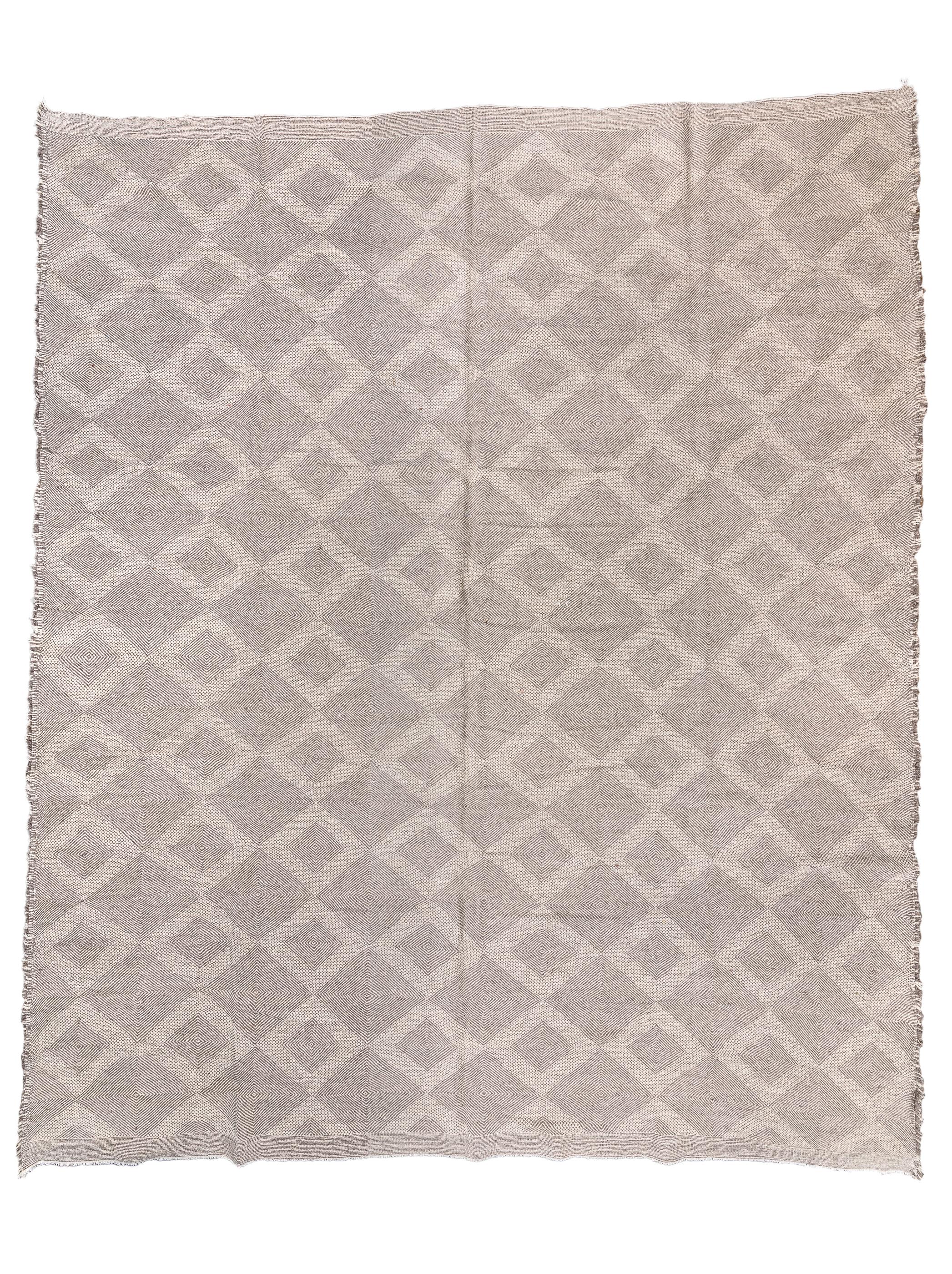 This pileless piece features a lattice of larger and smaller diamonds in light grey while the lattice is in pale grey. Or one could see it as columns of larger and smaller grey lozenges on a light field. Or darker, rough selvage makes a very skinny