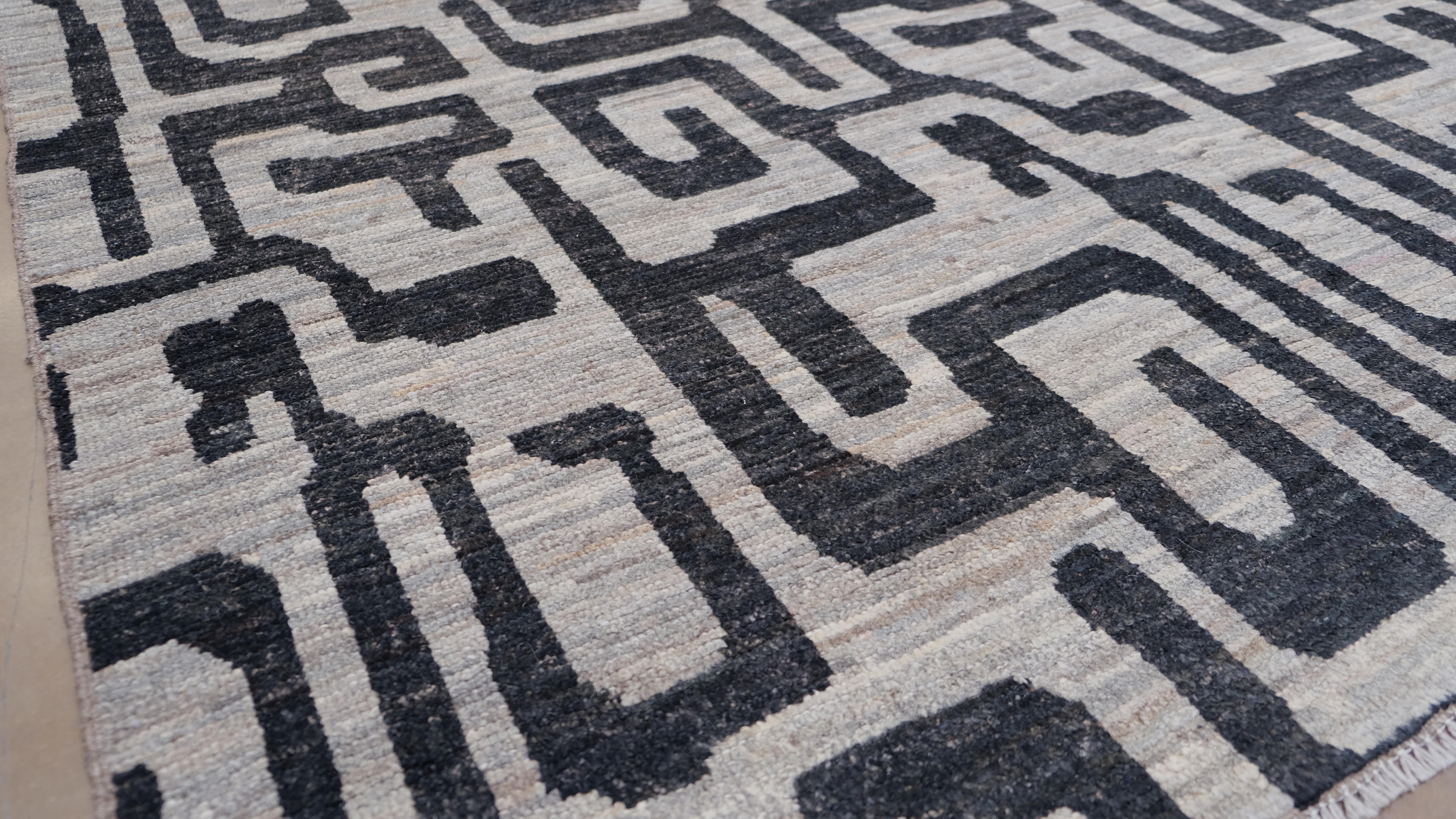 Arricchisci i tuoi interni con questo straordinario tappeto in lana annodato a mano con un audace disegno geometrico a labirinto in nero e grigio marrone. Con le sue dimensioni di 9'8