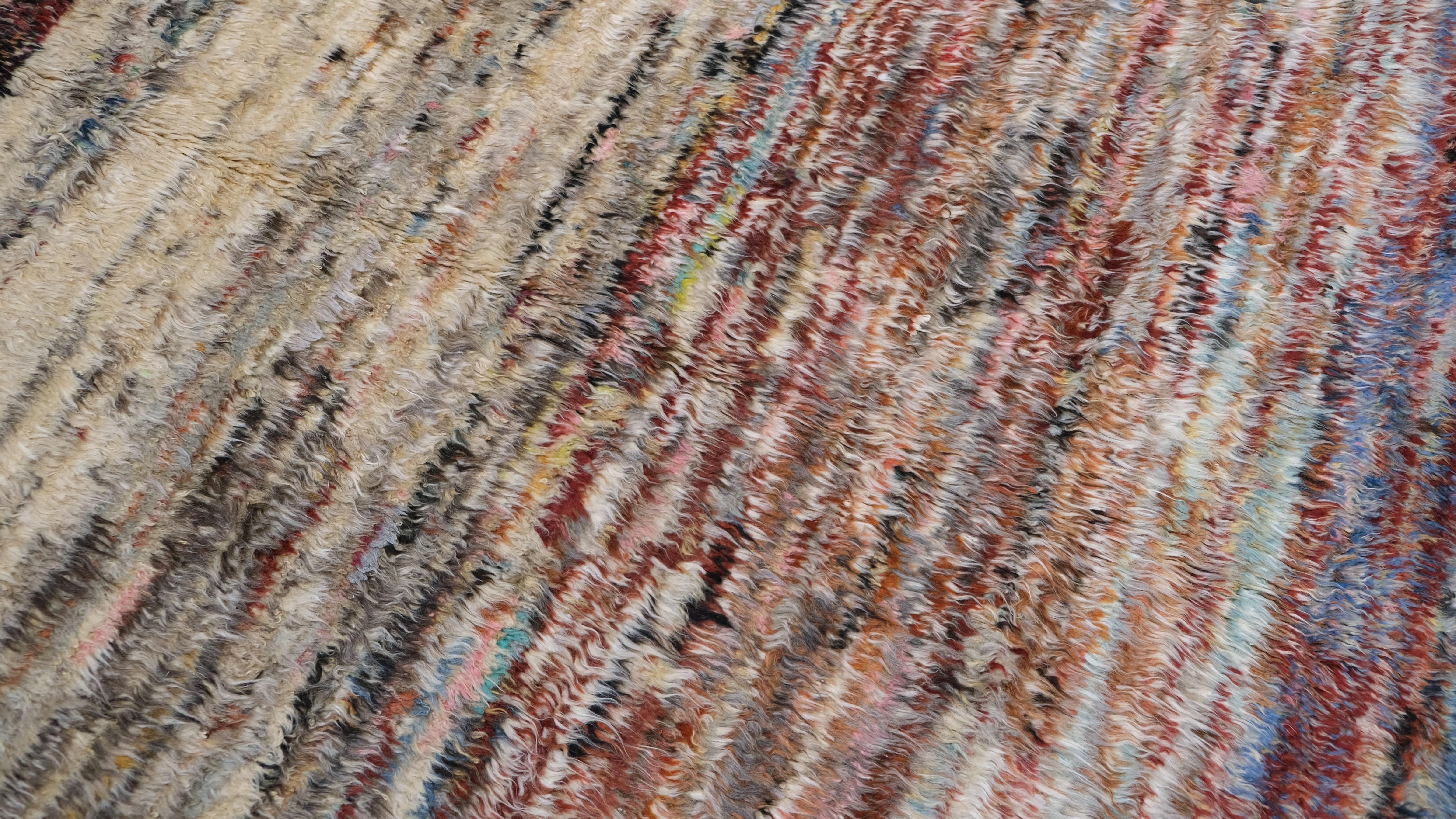 Dieser handgeknüpfte Wollteppich ist eine atemberaubende Darstellung von Stammes- und zeitgenössischer Kunstfertigkeit. Das abstrakte Streifenmuster in satten, erdigen Rot-, Beige-, Blau- und Brauntönen vermittelt ein Gefühl von Wärme und Textur und