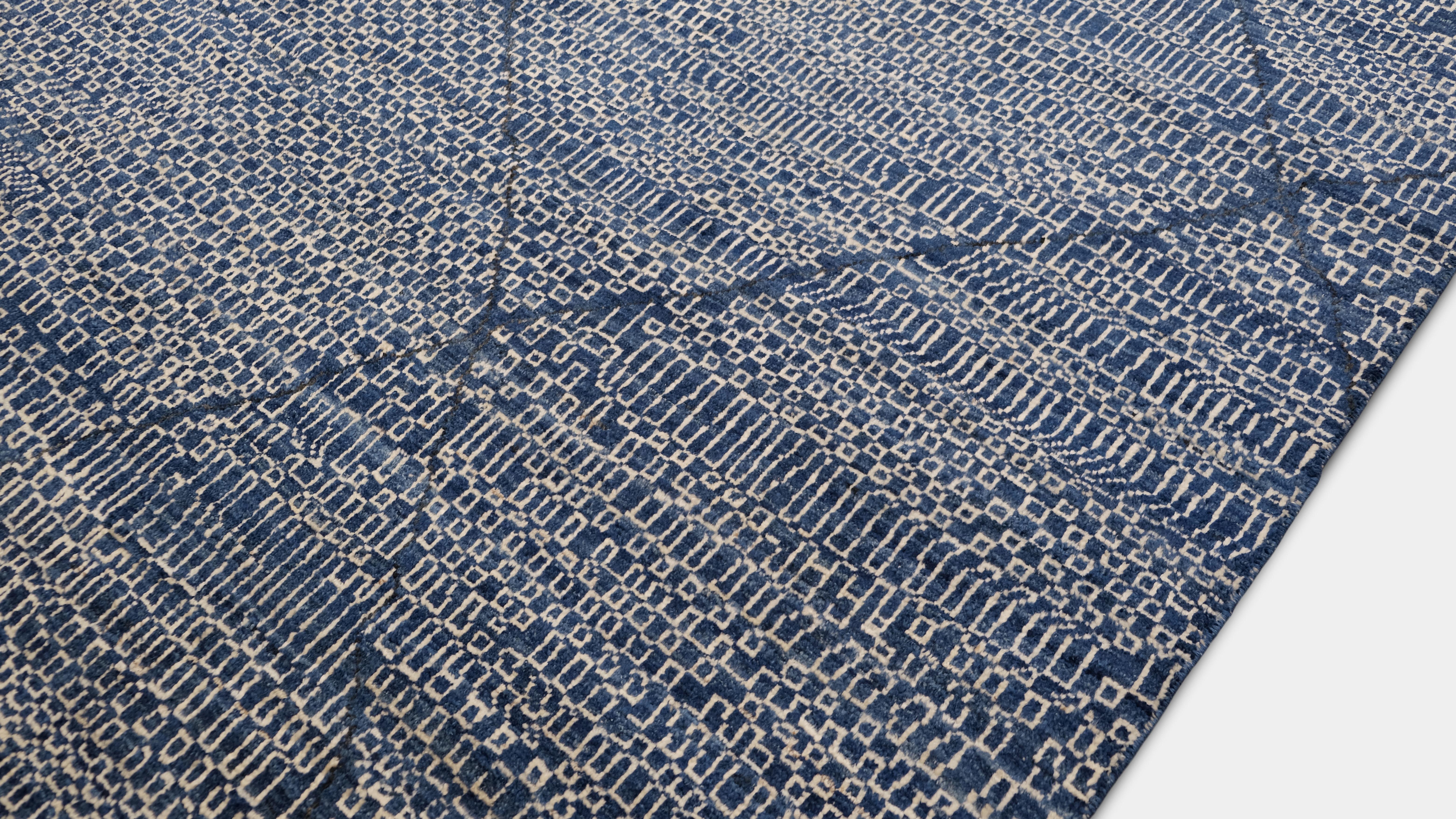 This hand-knotted wool rug beautifully blends modern tribal aesthetics with timeless craftsmanship. The intricate lattice pattern in indigo blue creates a bold yet versatile visual texture, making it a standout piece in contemporary, eclectic, or