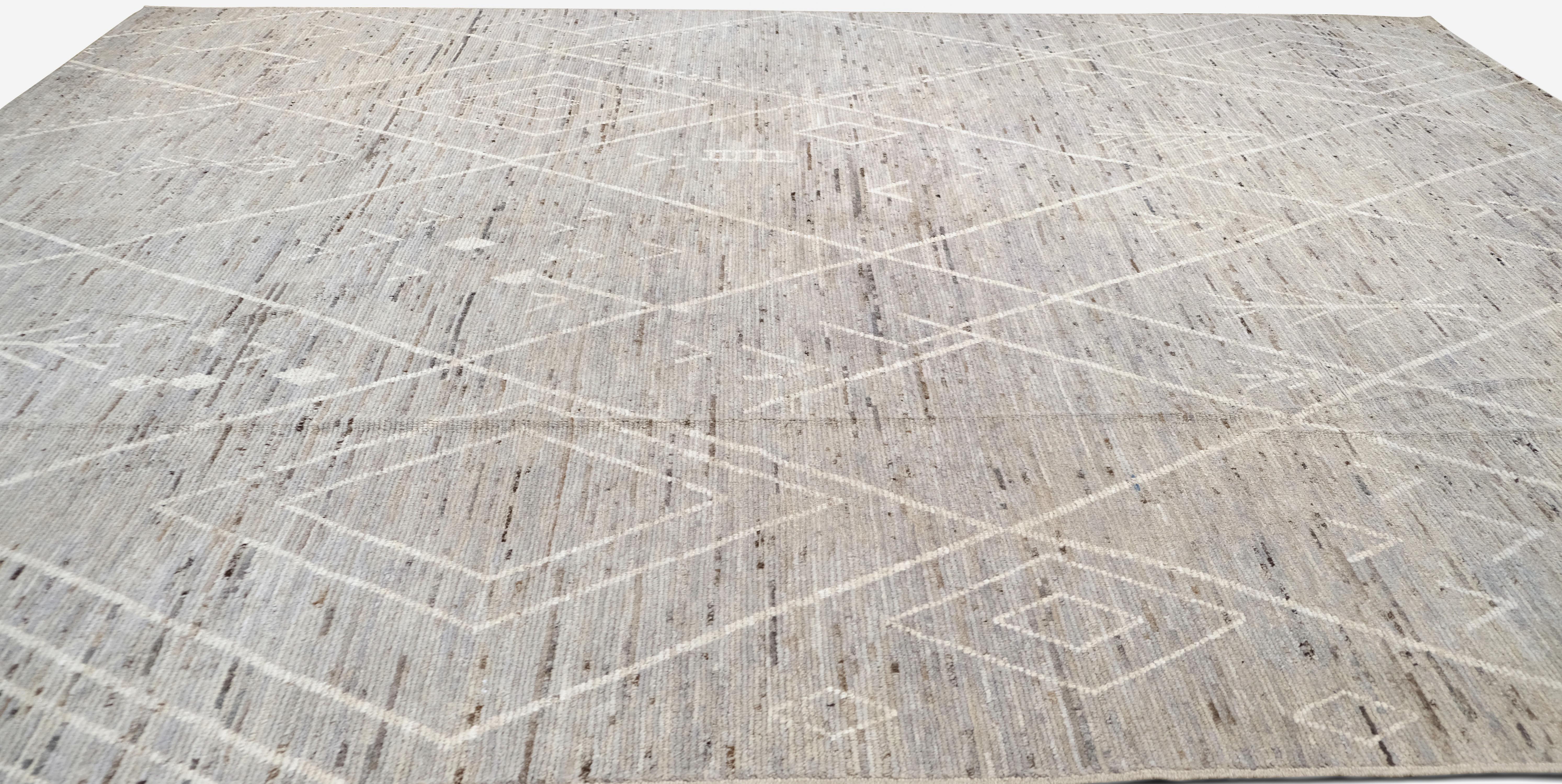 This hand-knotted wool rug beautifully merges traditional tribal patterns with a modern minimalist aesthetic. The design features an intricate network of geometric shapes, including diamond motifs and subtle linear patterns, which evoke classic