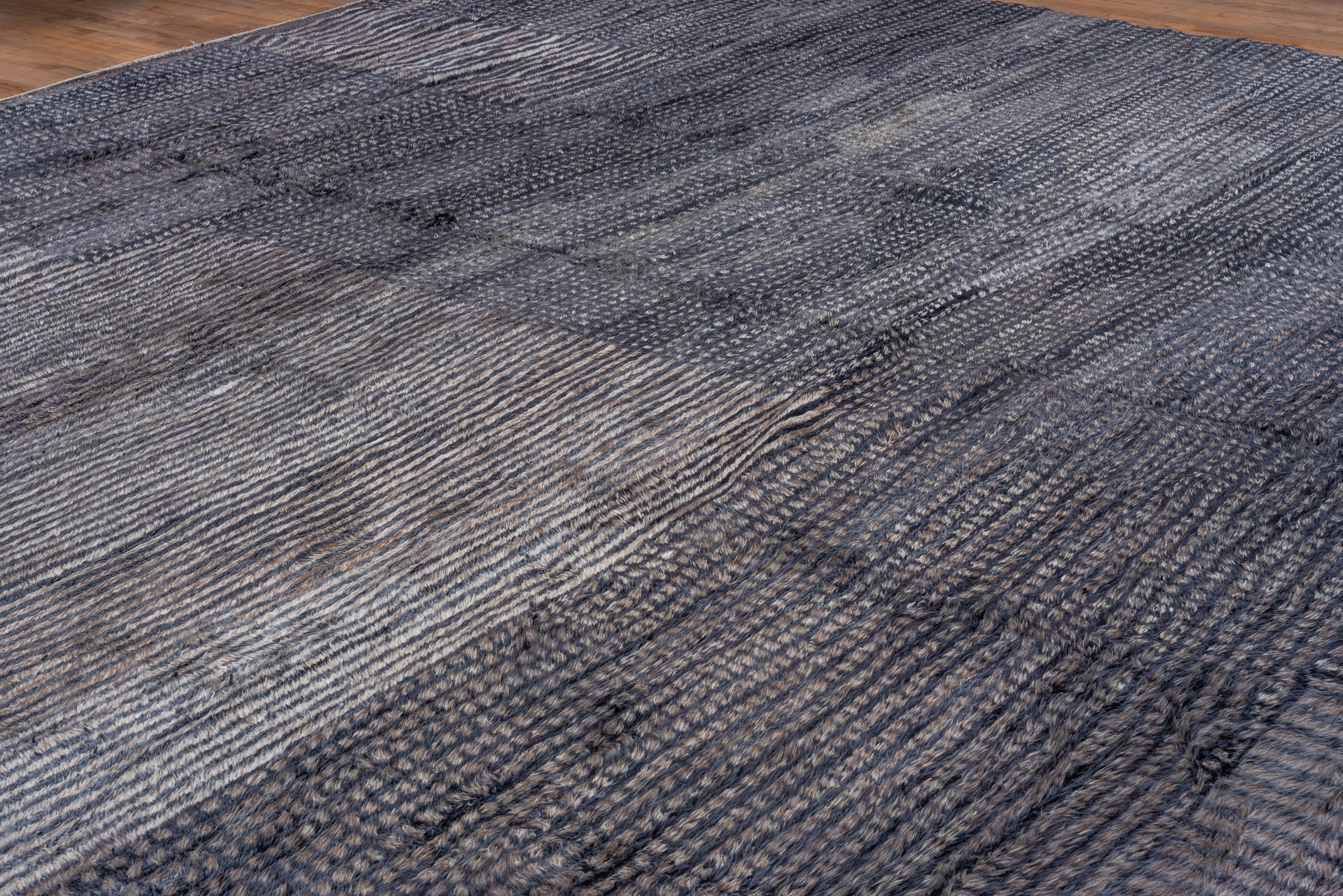 This long pile rustic carpet shows panels of lines running vertically and horizontally, and other sections with dense arrays of small dots, in light gray, dark gray and navy tones, borderless. Excellent brand new condition.