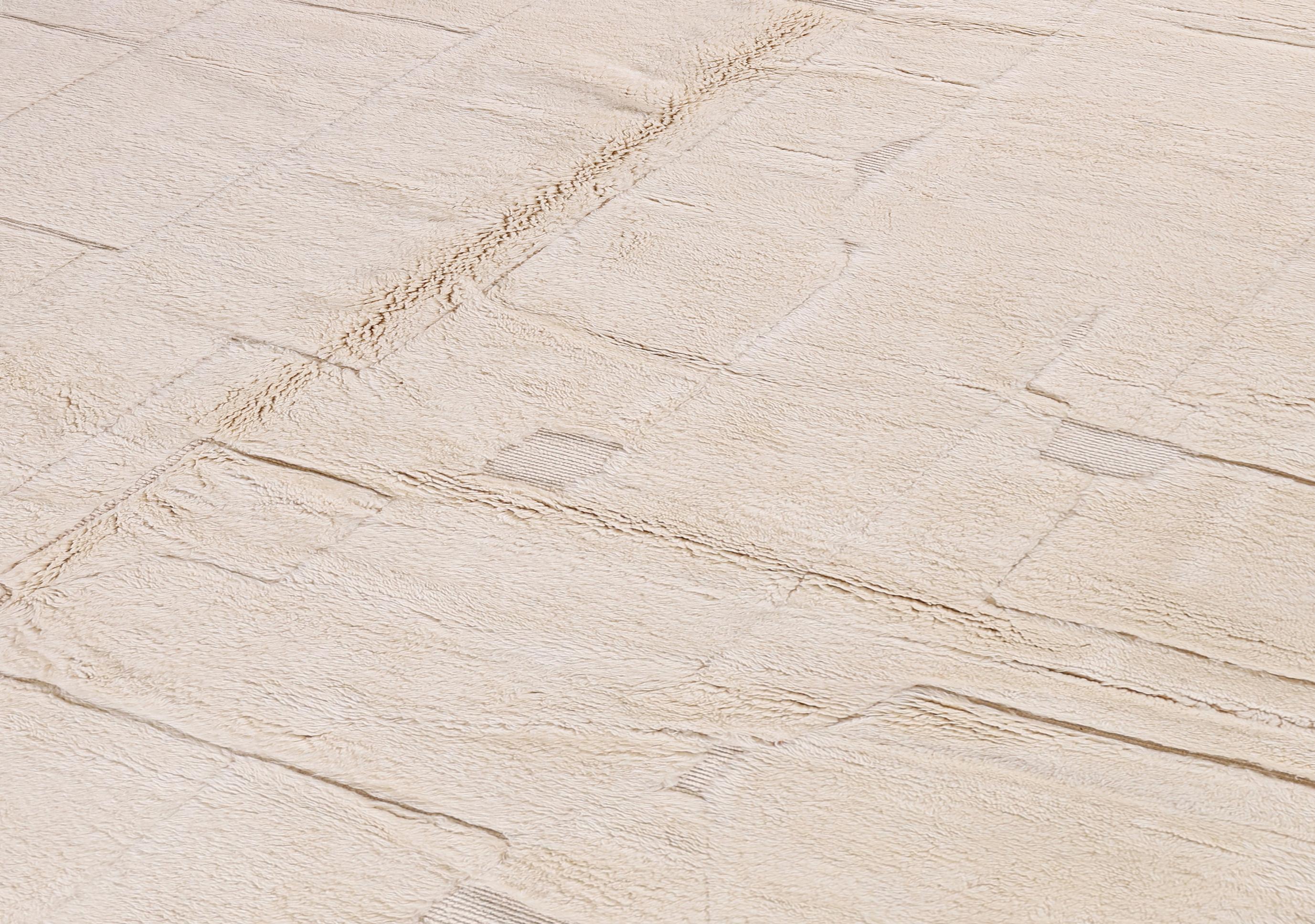 Questo moderno tappeto marocchino presenta una sofisticata miscela di texture e tonalità, realizzata interamente in lana avorio annodata a mano. Il suo design geometrico minimalista in rilievo, ottenuto grazie a una combinazione di tessitura a pelo