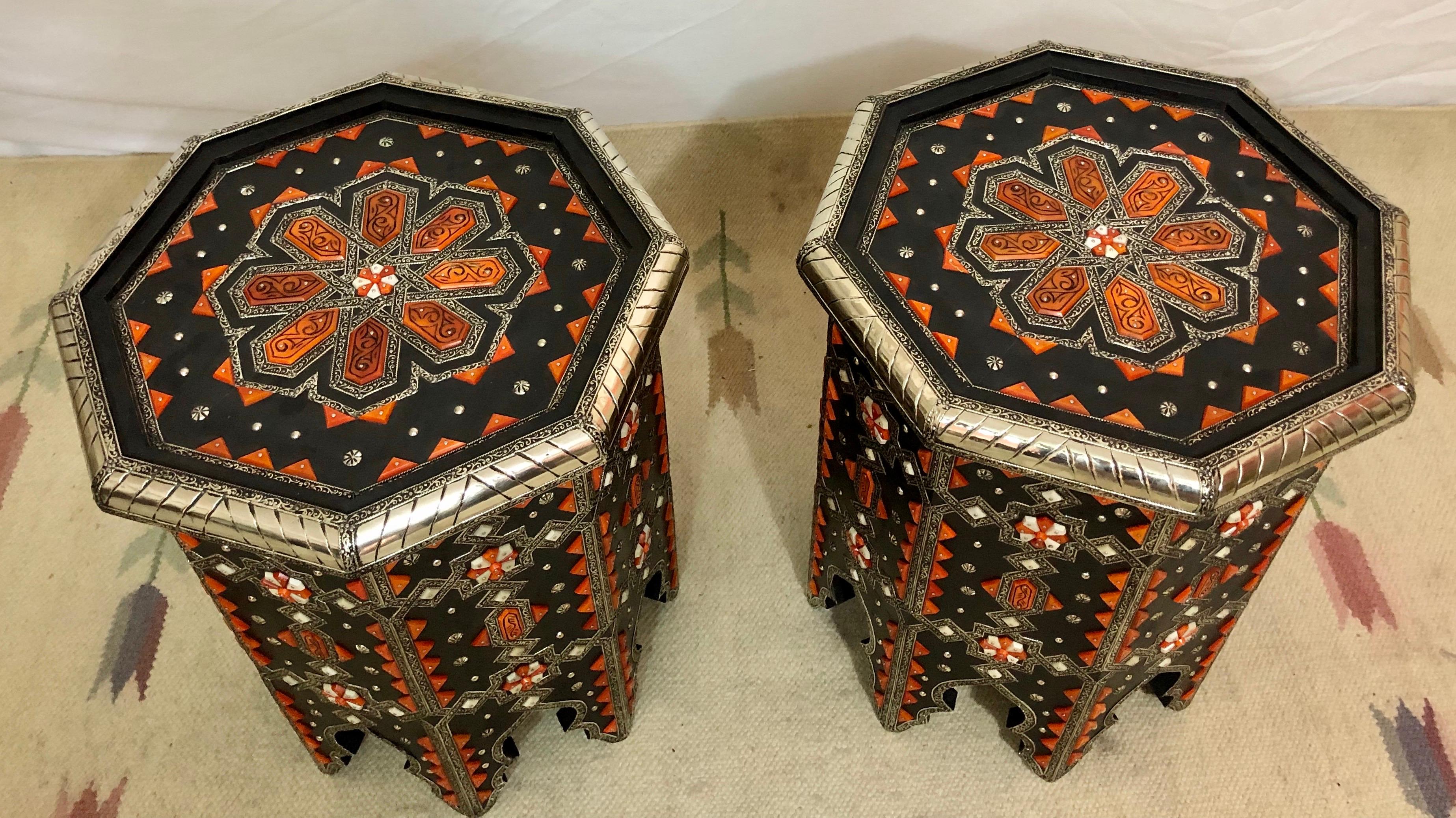 This luxurious wooden and white brass with orange camel bone inlay pair of tables is an exotic and sophisticated addition to any room. Featuring a beautifully complex and entrancing geometric pattern, dazzling color combinations and a beautifully