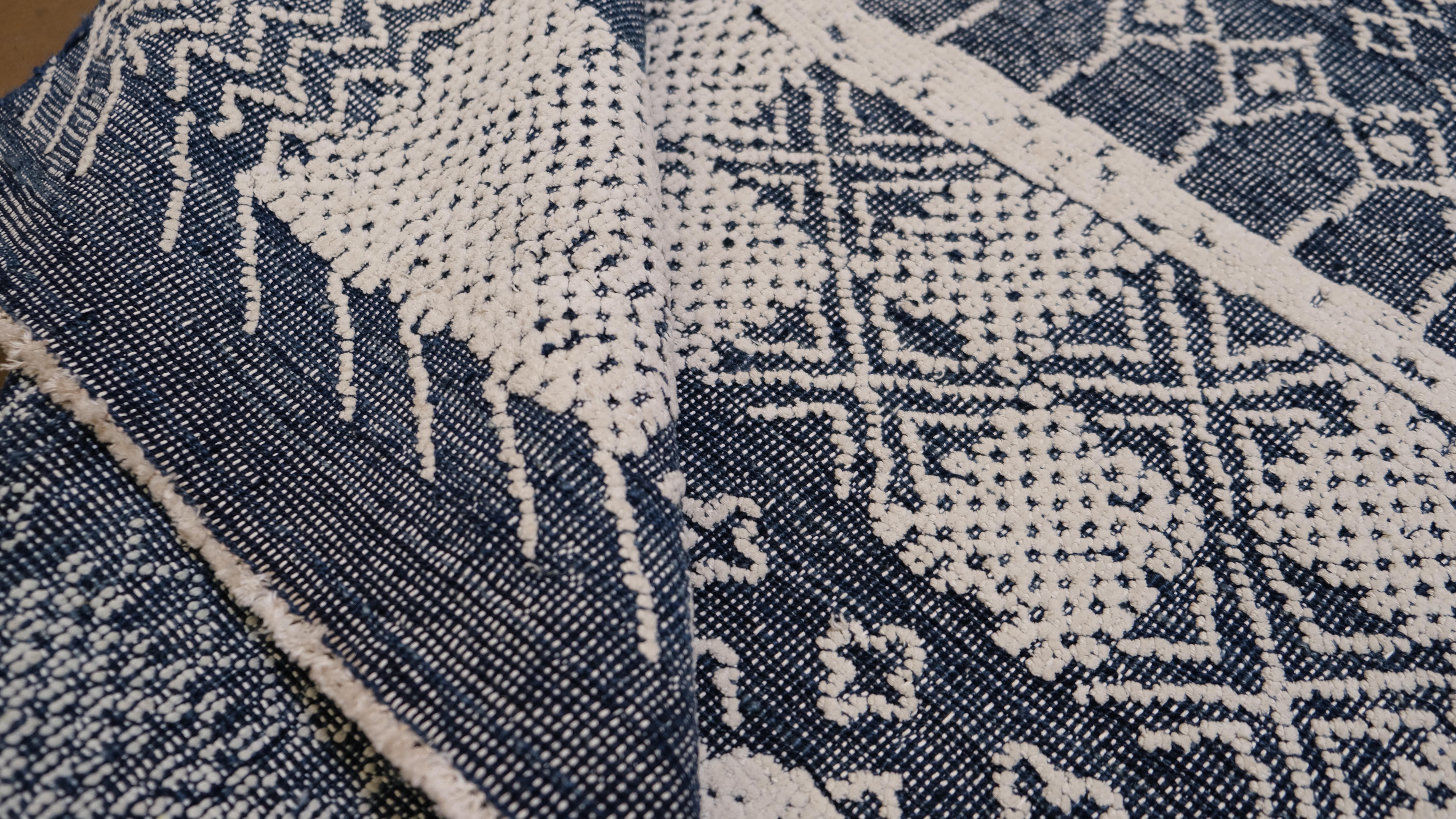 Elevate your interior with this stunning hand-knotted wool rug. Featuring a sophisticated blue and white design, this piece showcases a blend of intricate geometric and traditional patterns that pay homage to timeless craftsmanship. The detailed