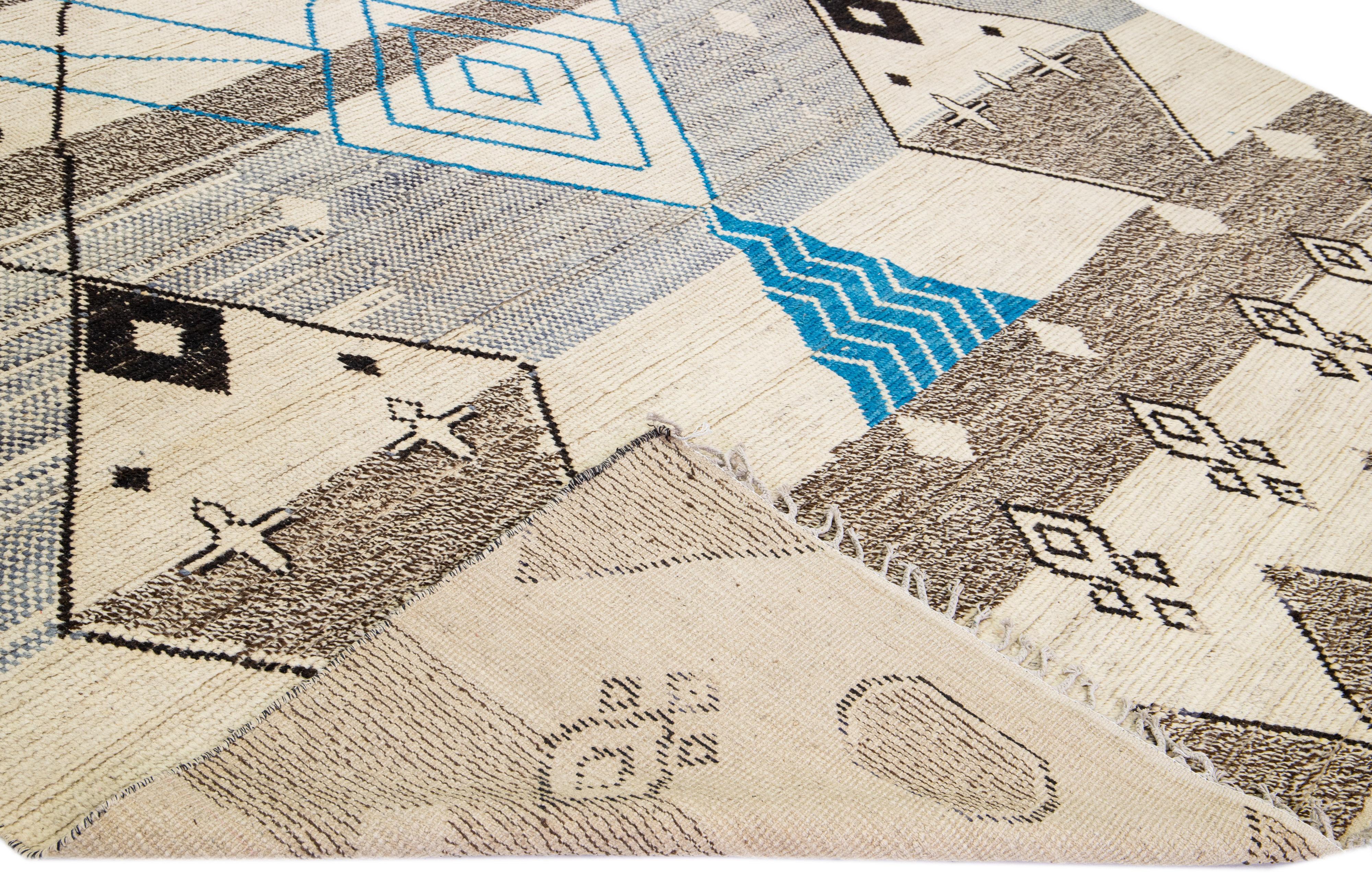Beautiful modern Moroccan style hand-knotted wool rug with a beige field. This piece has gray, brown, and blue accent color in a gorgeous tribal design with fringes on the top and bottom end.

This rug measures: 10'2