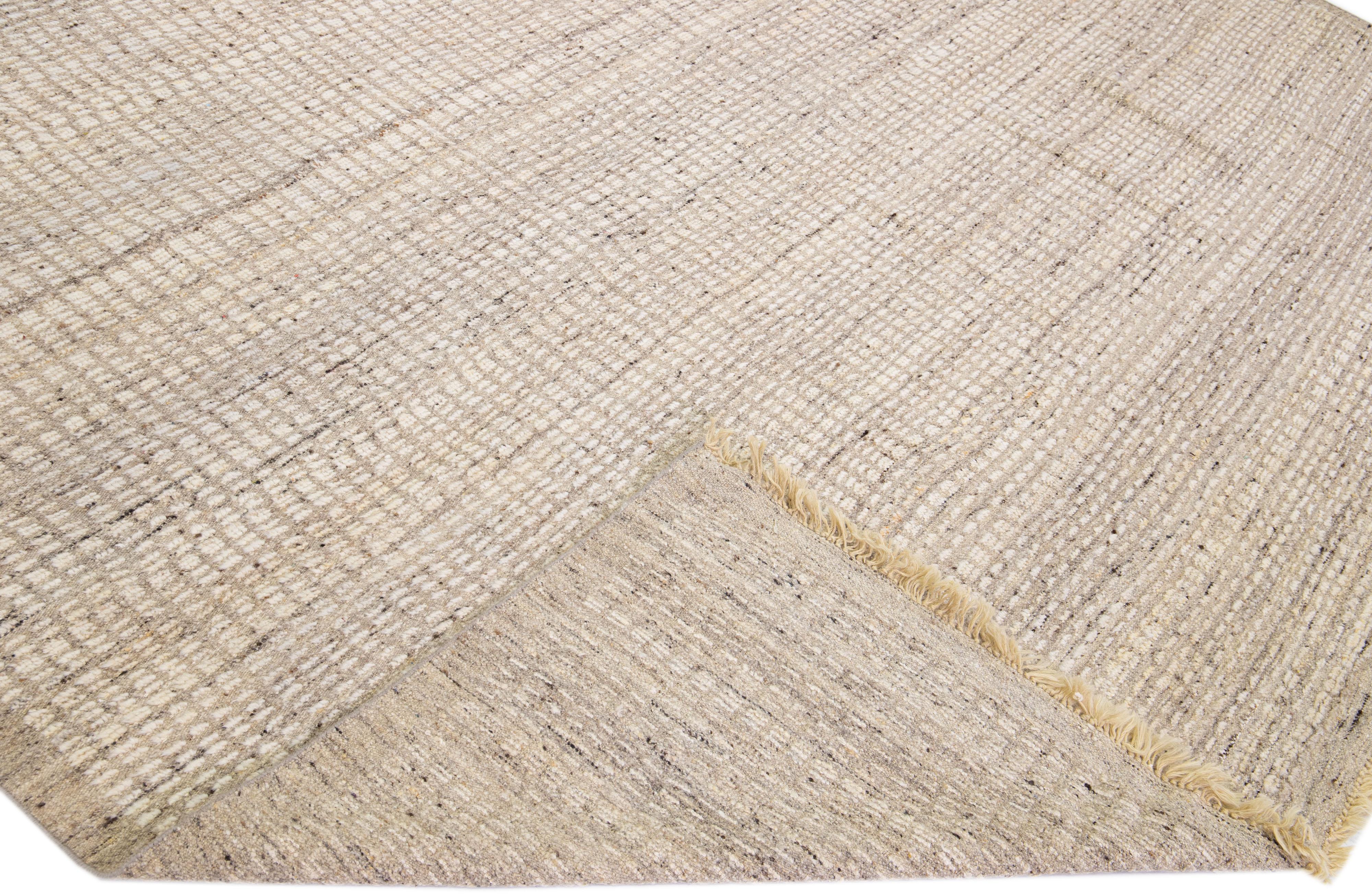 Beautiful modern Moroccan style hand-knotted wool rug with a beige and light brown field. This piece has a gorgeous subtle geometric pattern design with fringes on the top and bottom end.

This rug measures: 10'3