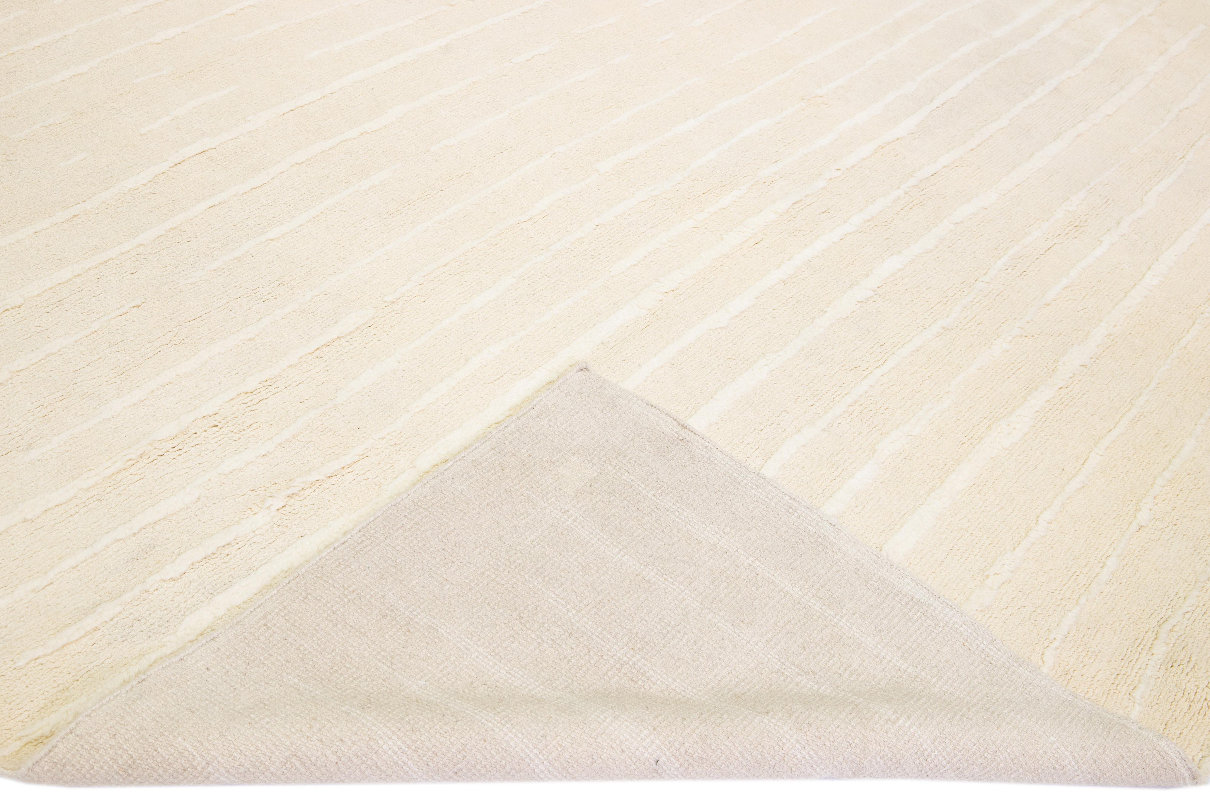 Magnifique tapis en laine fait main de style marocain avec un champ beige. Ce tapis moderne à l'accent ivoire présente un magnifique motif rayé sur toute sa surface.

Ce tapis mesure : 12' x 14'10
