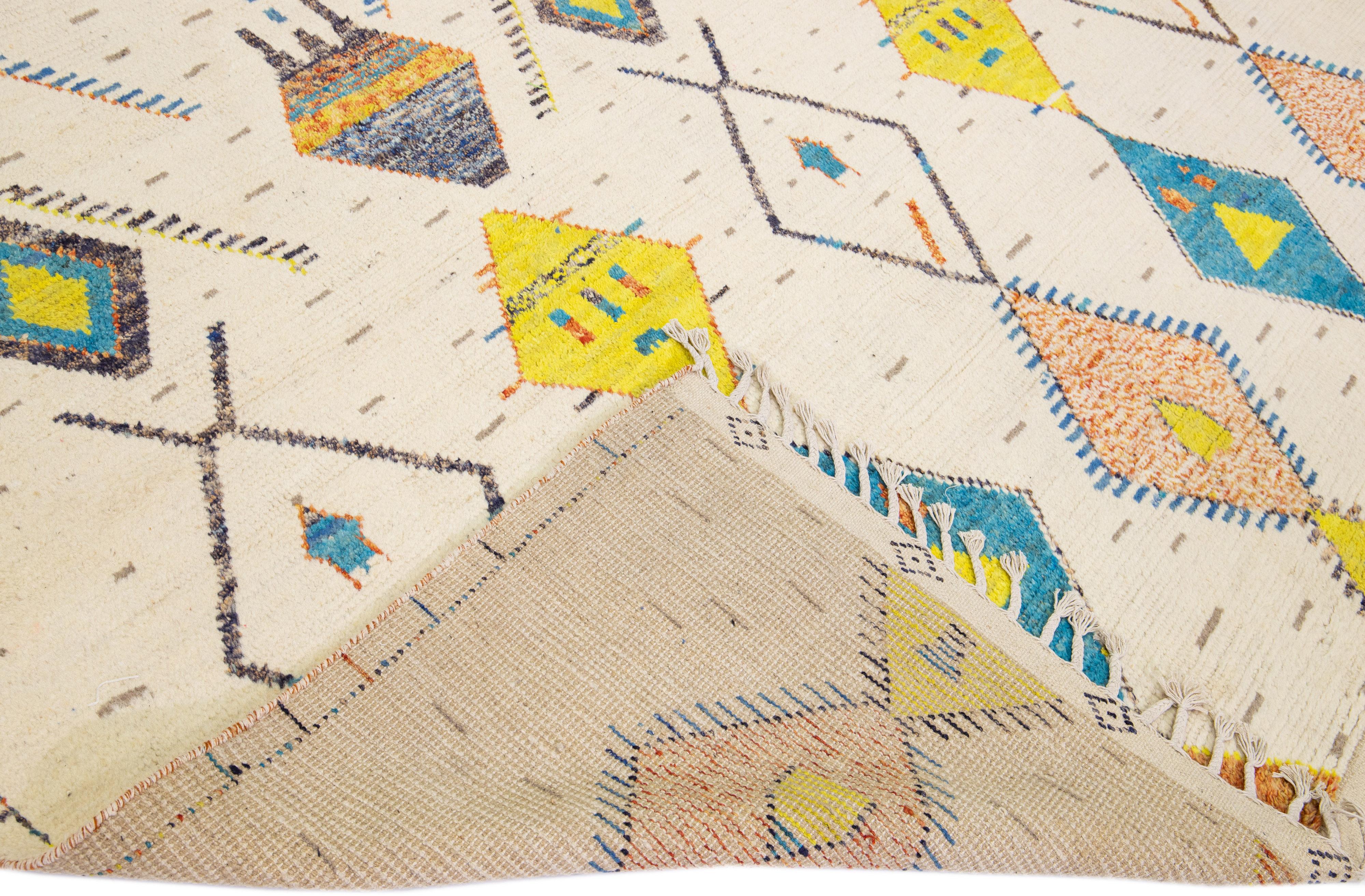 Beautiful modern Moroccan style hand-knotted wool rug with a beige field and fringes on the top and bottom end. This piece has orange, blue, gray, and yellow accent colors in a gorgeous tribal design.

This rug measures: 10' x 14'6