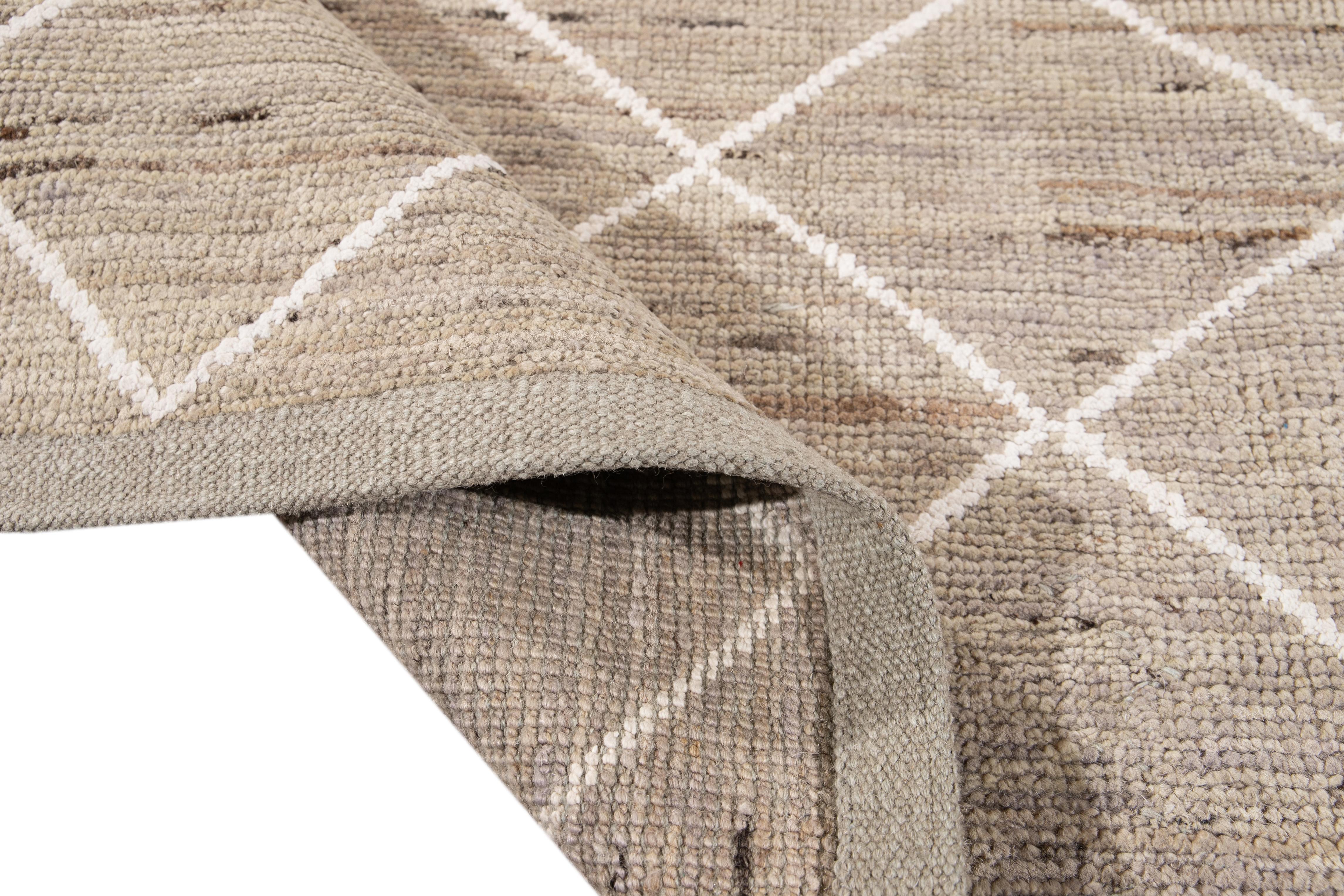 Magnifique tapis de style marocain en laine nouée à la main avec un champ beige. Ce tapis présente des accents de blanc dans un magnifique motif géométrique tribal.

Ce tapis mesure 8'2