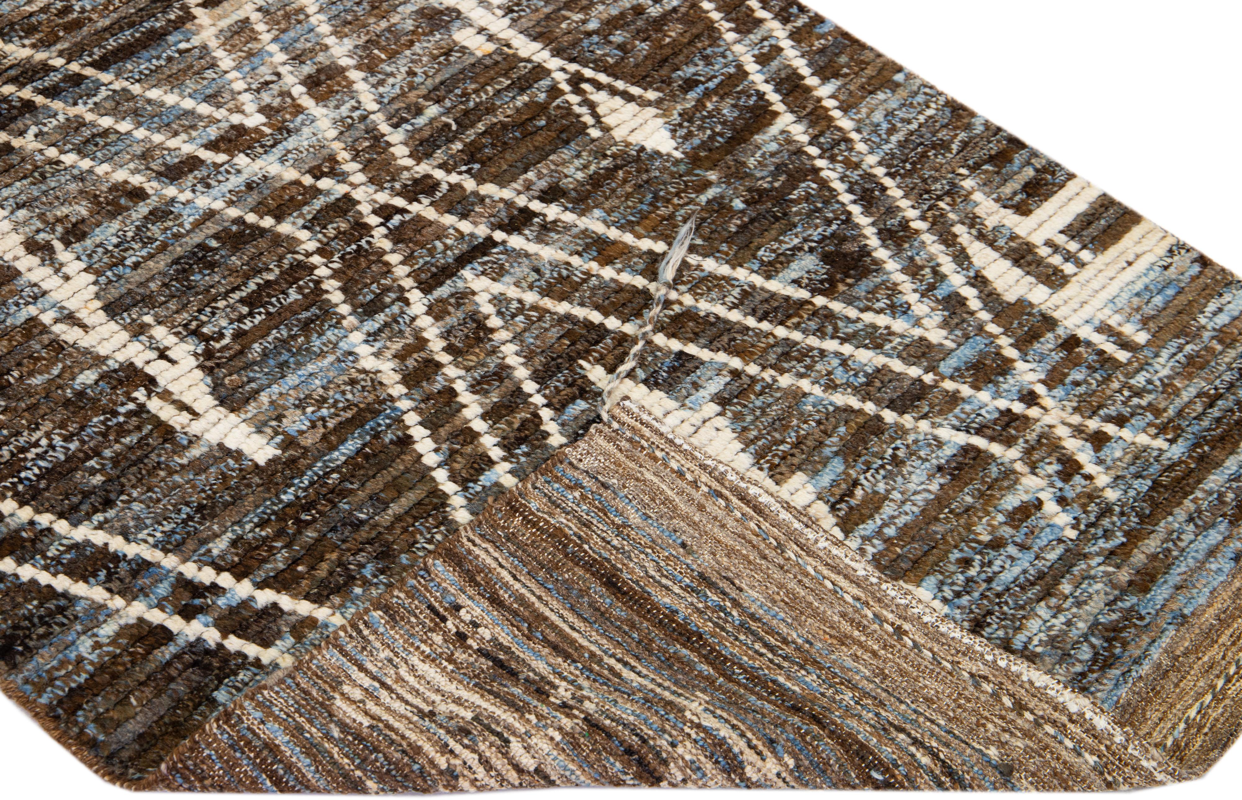 Magnifique tapis en laine fait main de style marocain avec un champ marron et bleu. Ce tapis moderne aux accents ivoires présente un magnifique motif tribal sur toute sa surface.

Ce tapis mesure : 3'3