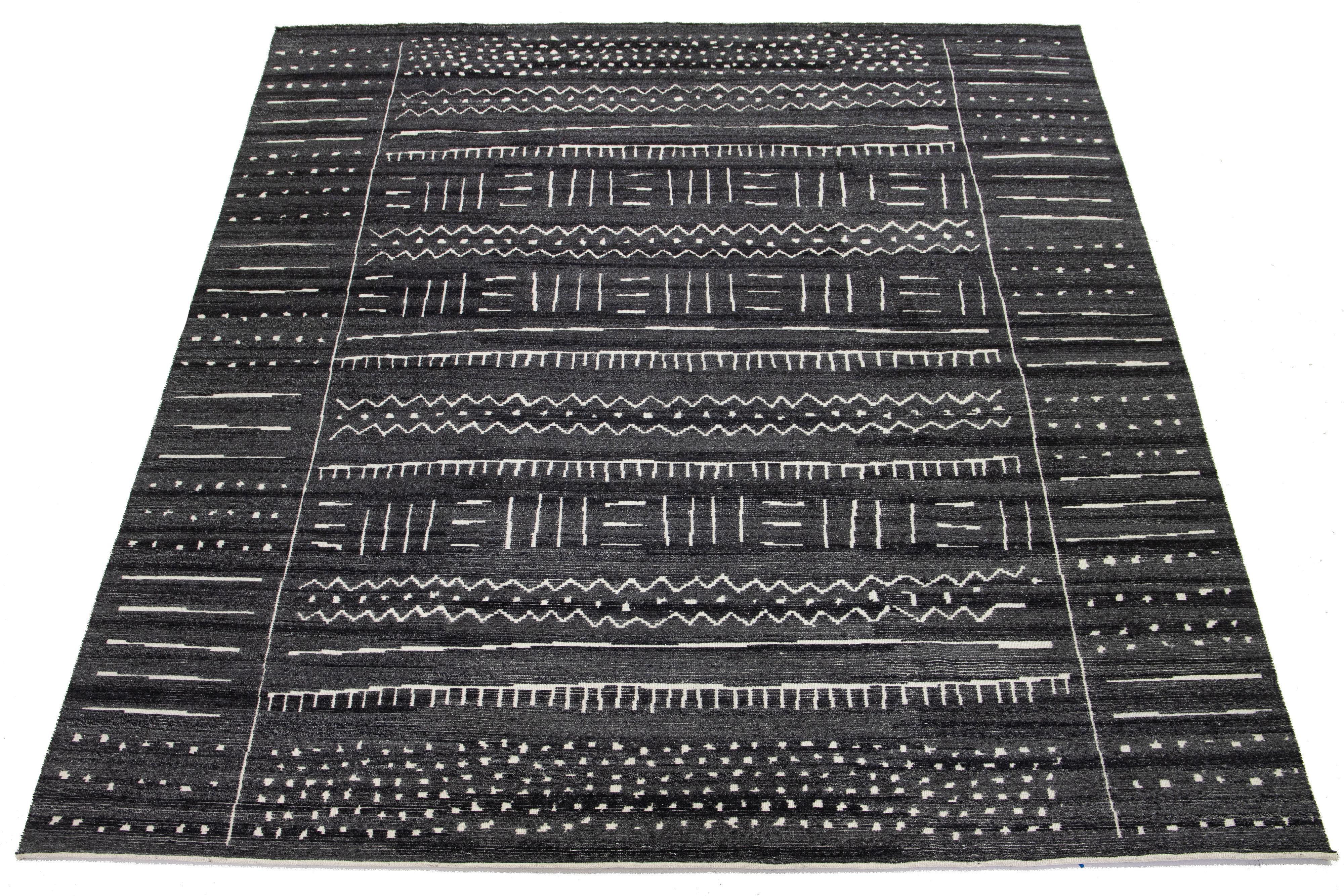 Ce tapis en laine noué à la main dans un style marocain contemporain présente un riche champ gris anthracite et ivoire orné d'un motif géométrique accrocheur. Cette pièce étonnante rehaussera l'esthétique de n'importe quel espace.

Ce tapis mesure