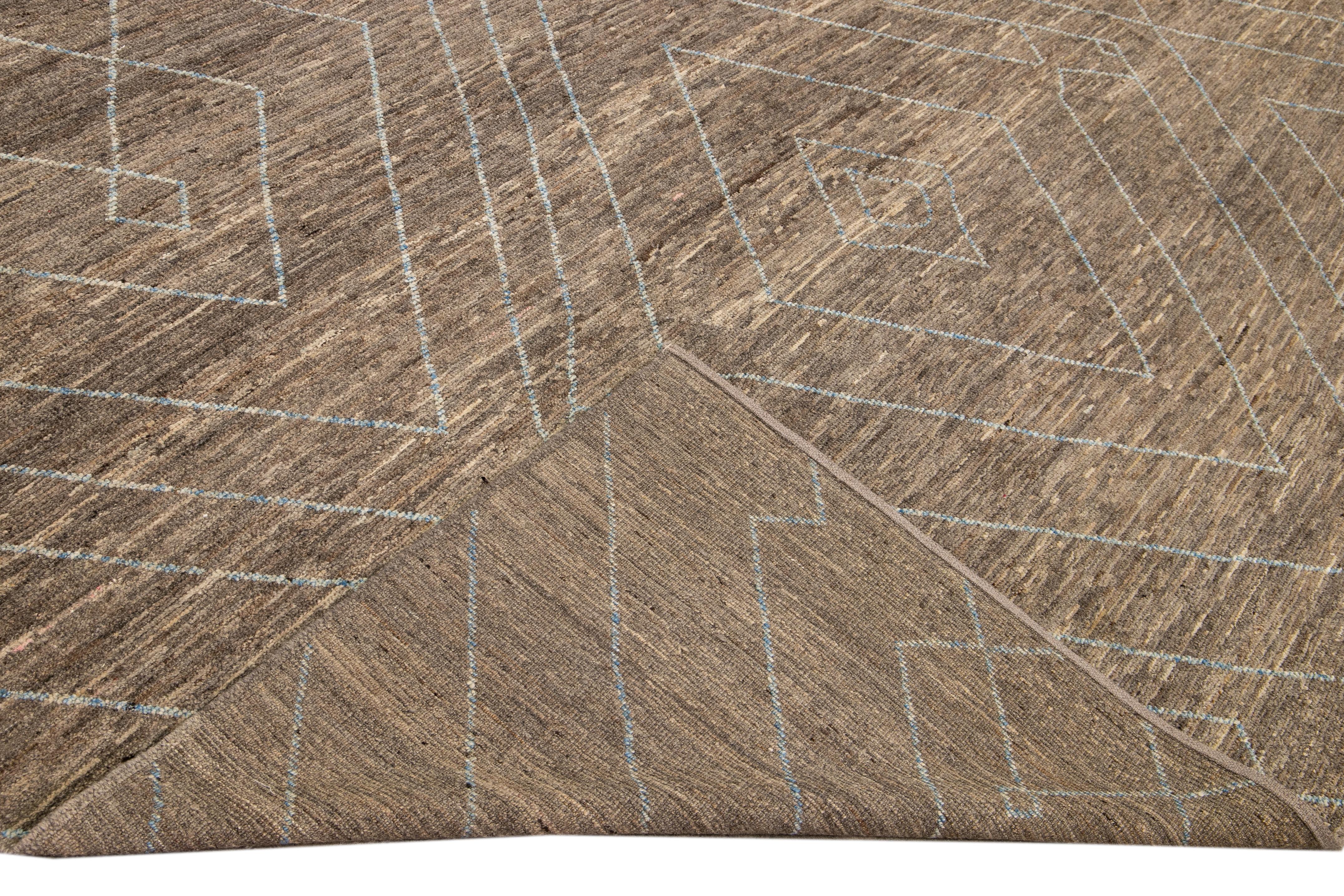 Magnifique tapis en laine fait main de style marocain avec un champ brun. Ce tapis moderne aux accents beige et bleu présente un magnifique motif géométrique sur toute sa surface.

Ce tapis mesure : 9'11