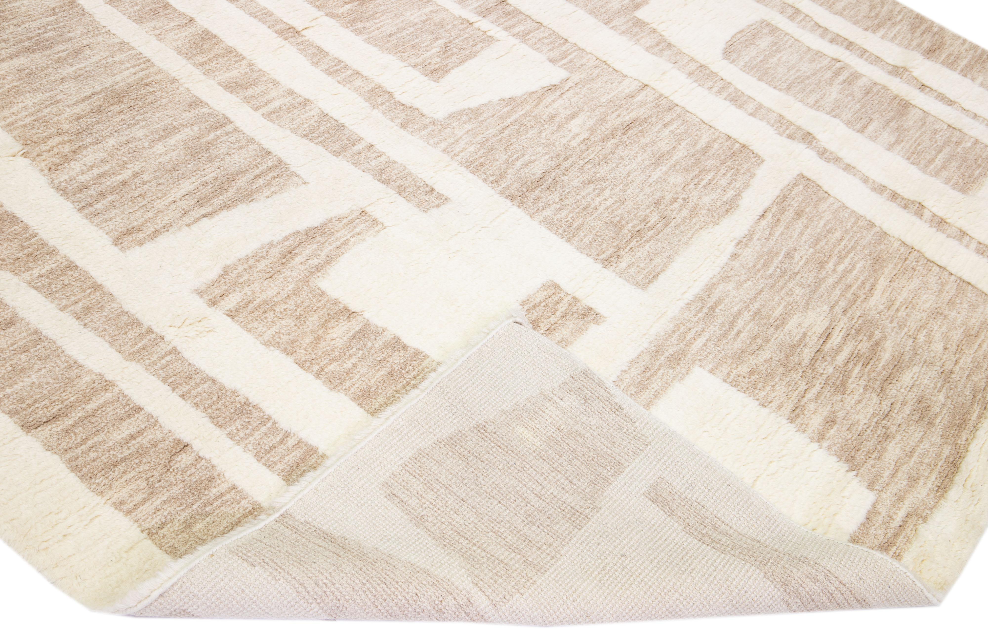 Beautiful modern Moroccan style hand-knotted wool rug with a light brown color field and ivory accents in a gorgeous geometric abstract high pile design.

This rug measures: 10'1