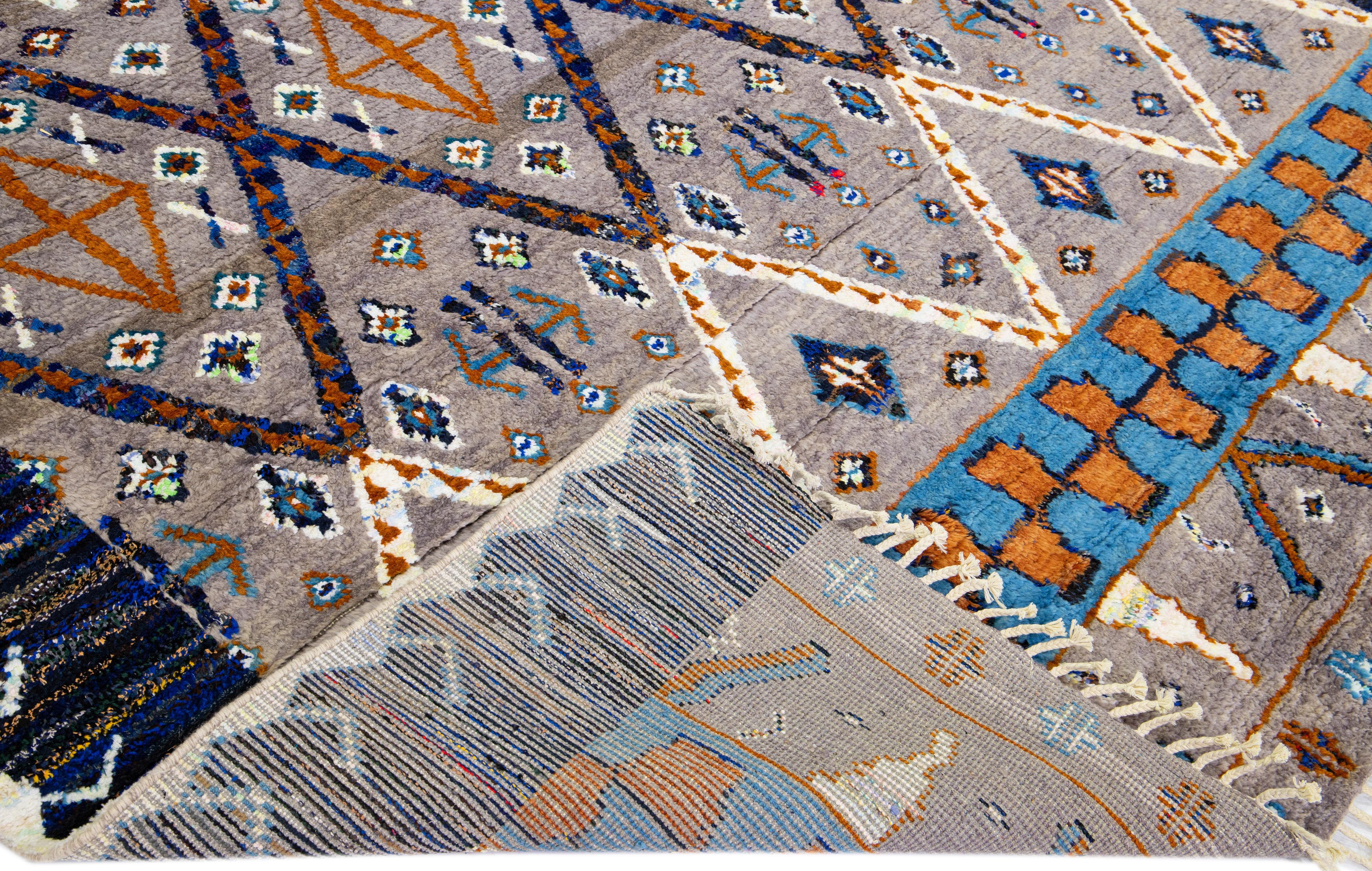 Magnifique tapis moderne de style marocain en laine nouée à la main avec un champ gris et brun. Cette pièce a une couleur d'accent multicolore dans un magnifique design tribal avec des franges sur l'extrémité supérieure et inférieure.

Ce tapis