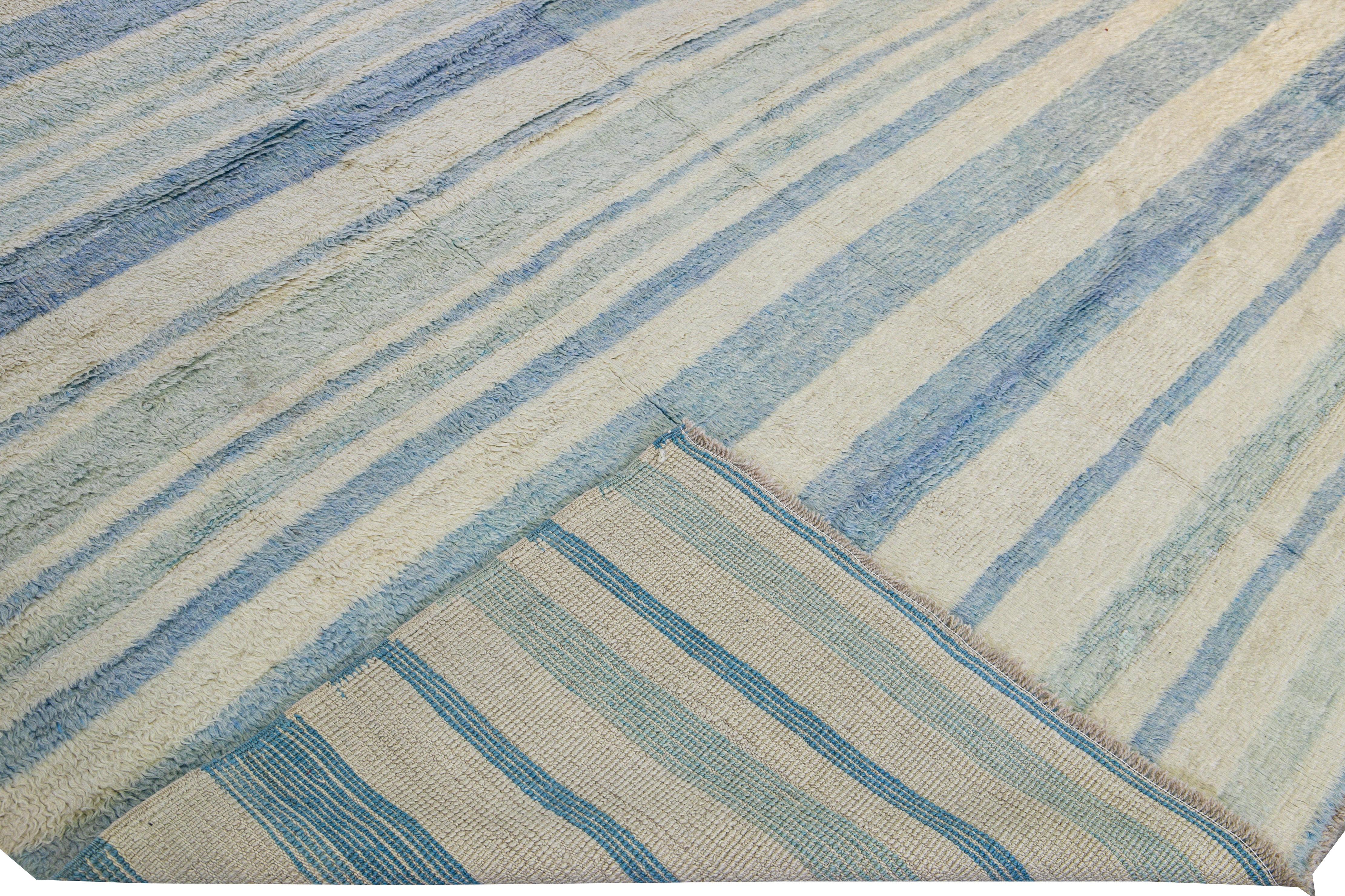Beautiful Moroccan style handmade wool rug with an ivory and blue field. This Modern rug features a gorgeous all-over geometric stripe design.

This rug measures: 9' x 12'6