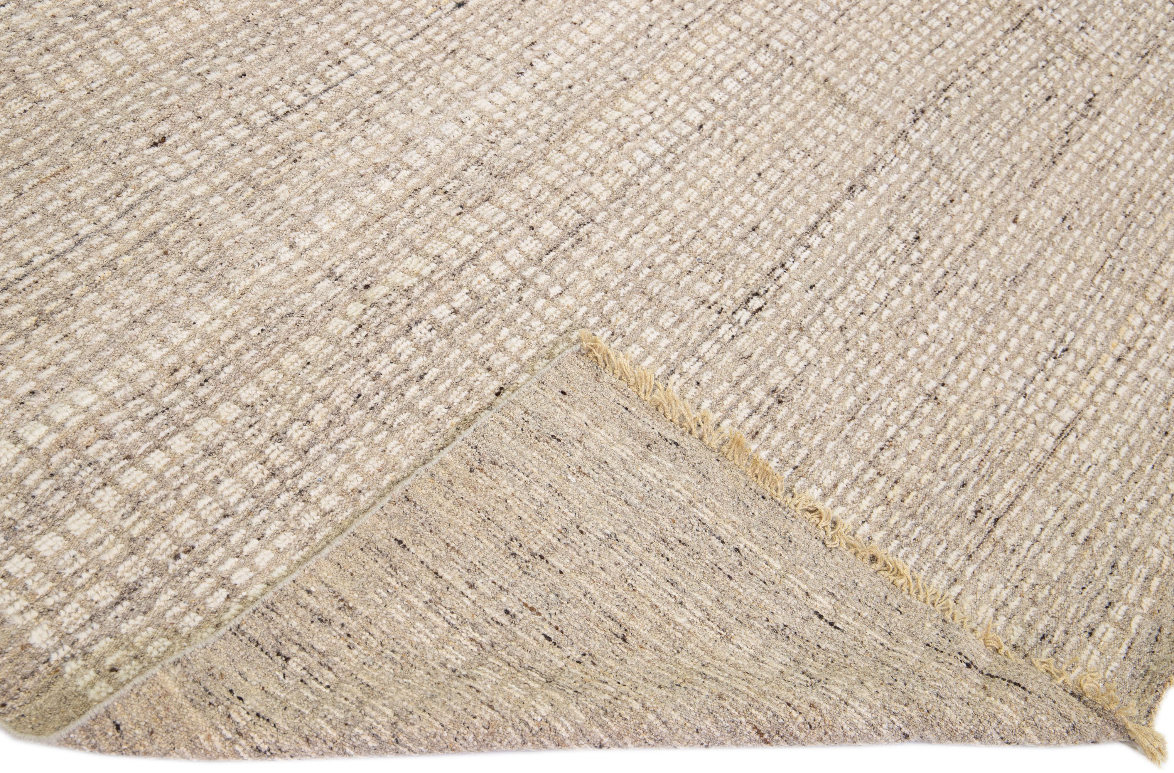 Beautiful modern Moroccan style hand-knotted wool rug with a beige field. This piece has a gorgeous subtle geometric pattern design.

This rug measures: 9'4