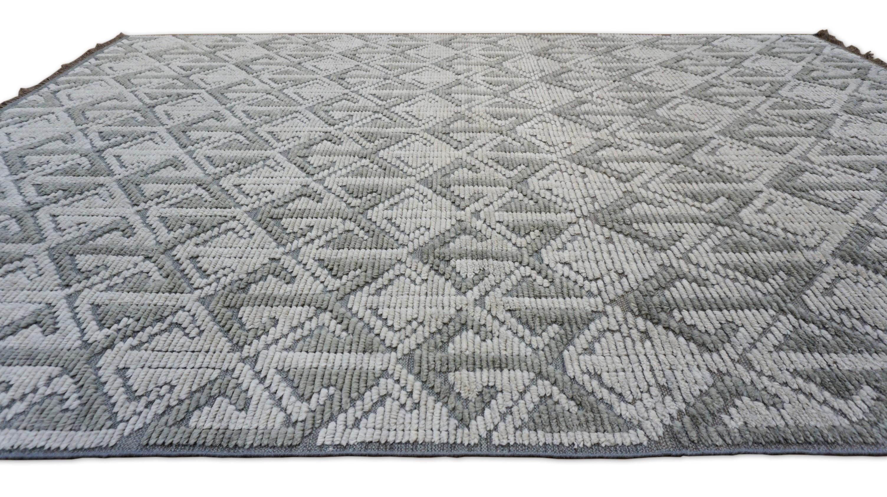 This contemporary hand-knotted wool rug features a bold geometric design of interlocking arrow motifs in a sophisticated palette of mink gray. The repeating pattern creates a visually arresting, rhythmic structure that adds dimension and modern