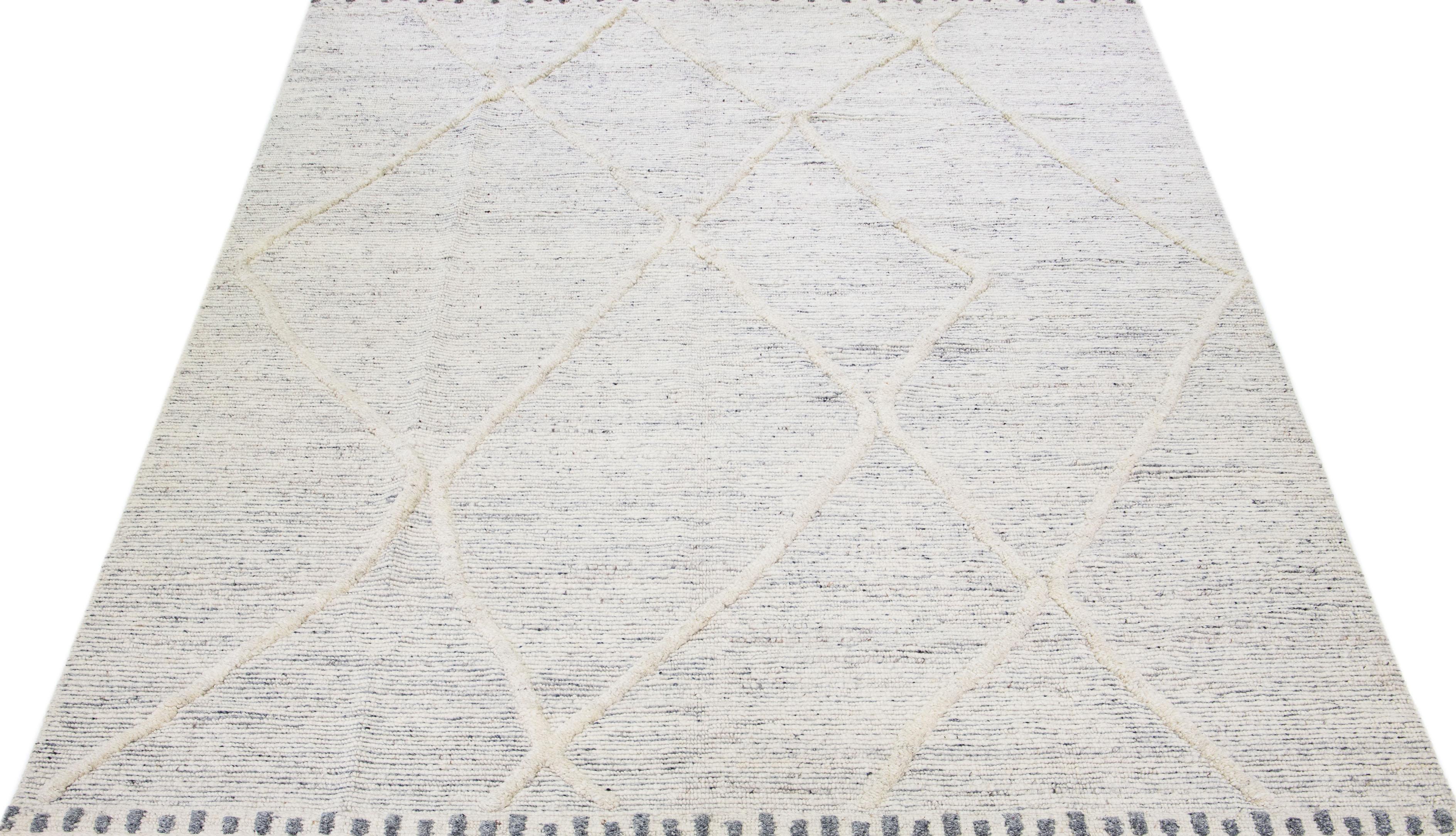 Schöner handgefertigter Wollteppich im marokkanischen Stil mit elfenbeinfarbenem Feld. Dieser moderne Teppich hat graue Akzente und ein wunderschönes geometrisches Boho-Motiv, das überall zu sehen ist.

Dieser Teppich misst: 10'2