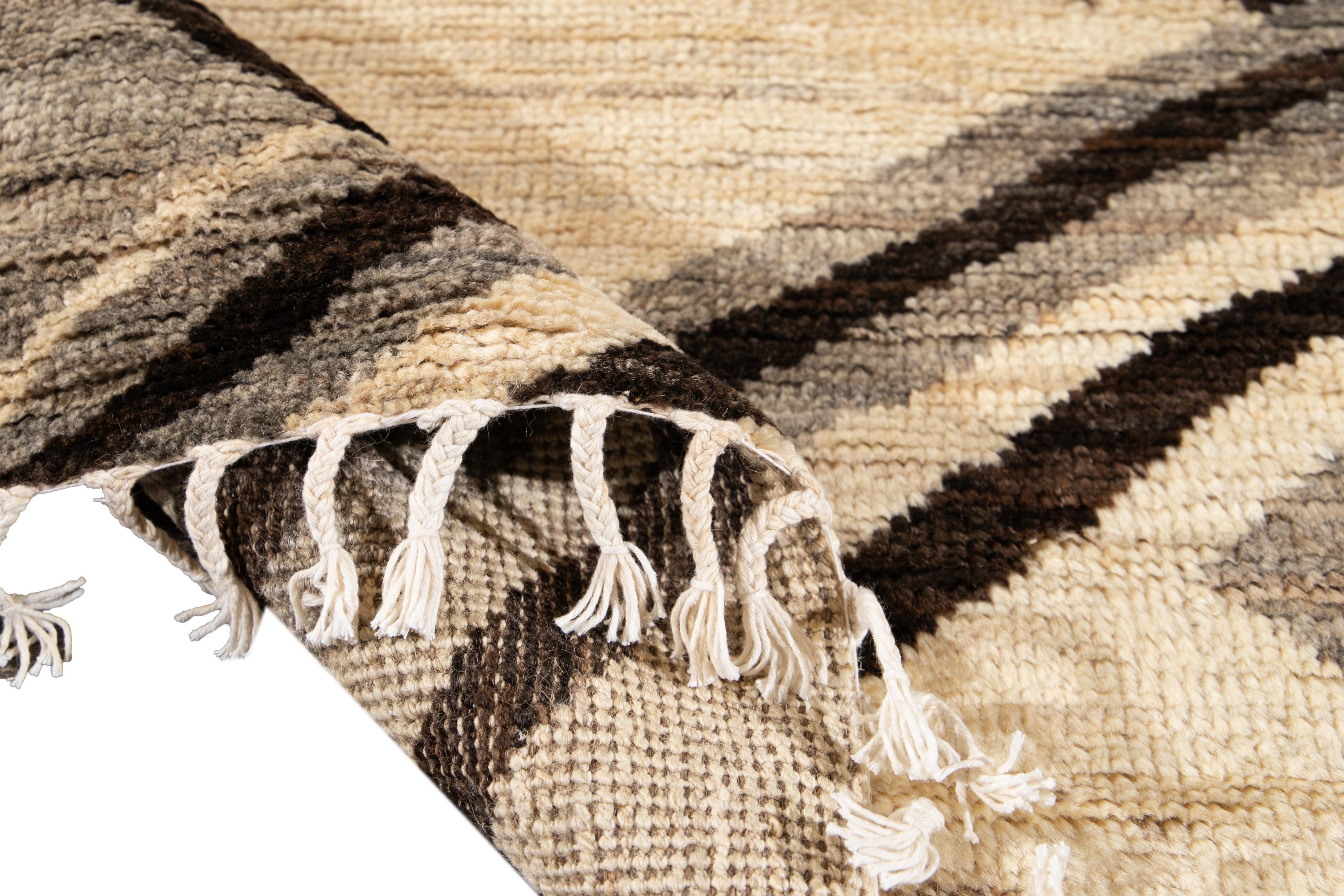 Magnifique tapis de style marocain en laine nouée à la main avec un champ beige. Ce tapis présente des accents de gris et de brun dans un magnifique motif abstrait géométrique.

Ce tapis mesure 8'4