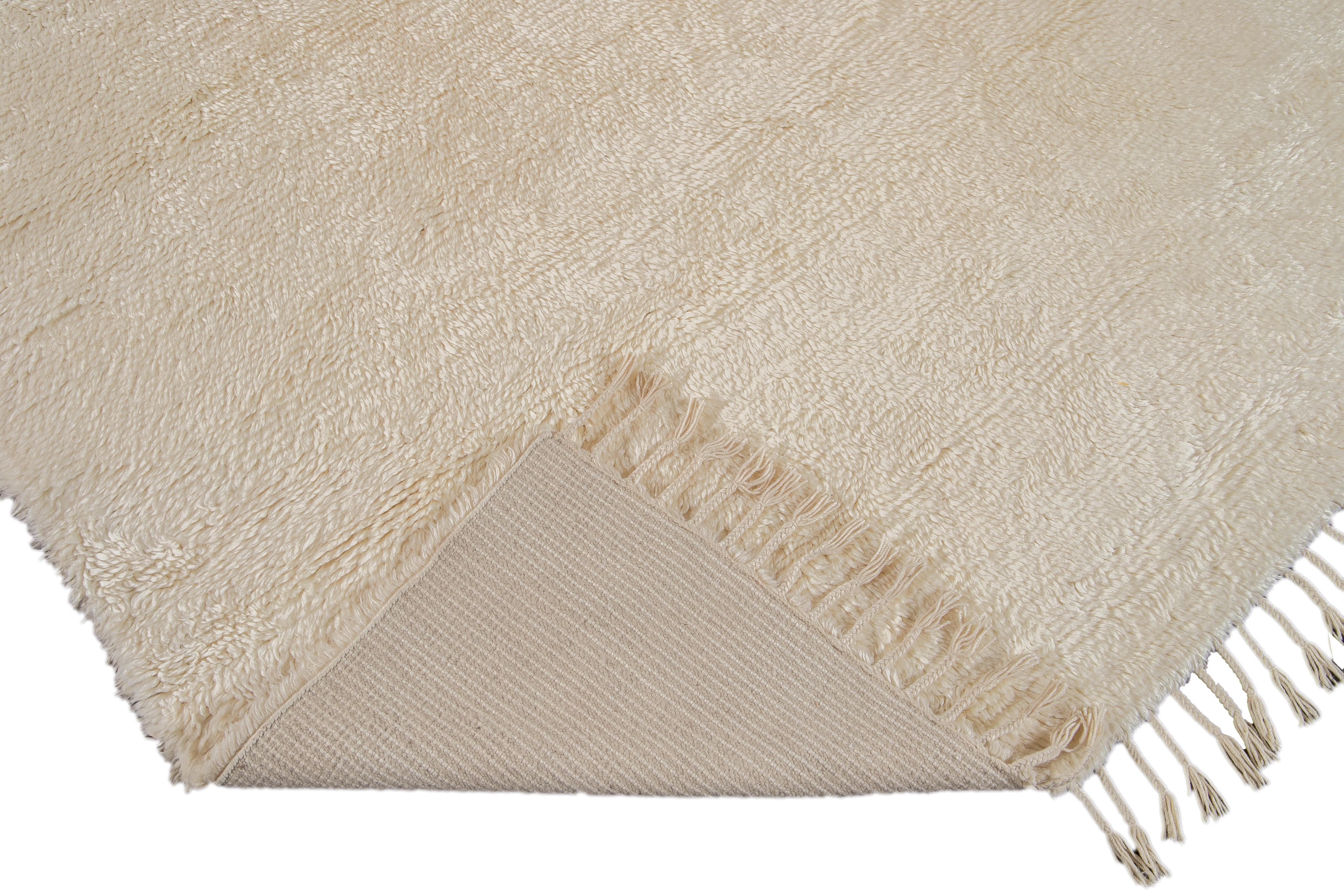 Schöner handgeknüpfter Wollteppich im zeitgenössischen marokkanischen Stil. Dieser Shag-Teppich hat das Feld und die Fransen von Ivory in einem herrlichen Shag-Design.

Dieser Teppich misst 9' x 12'.

 