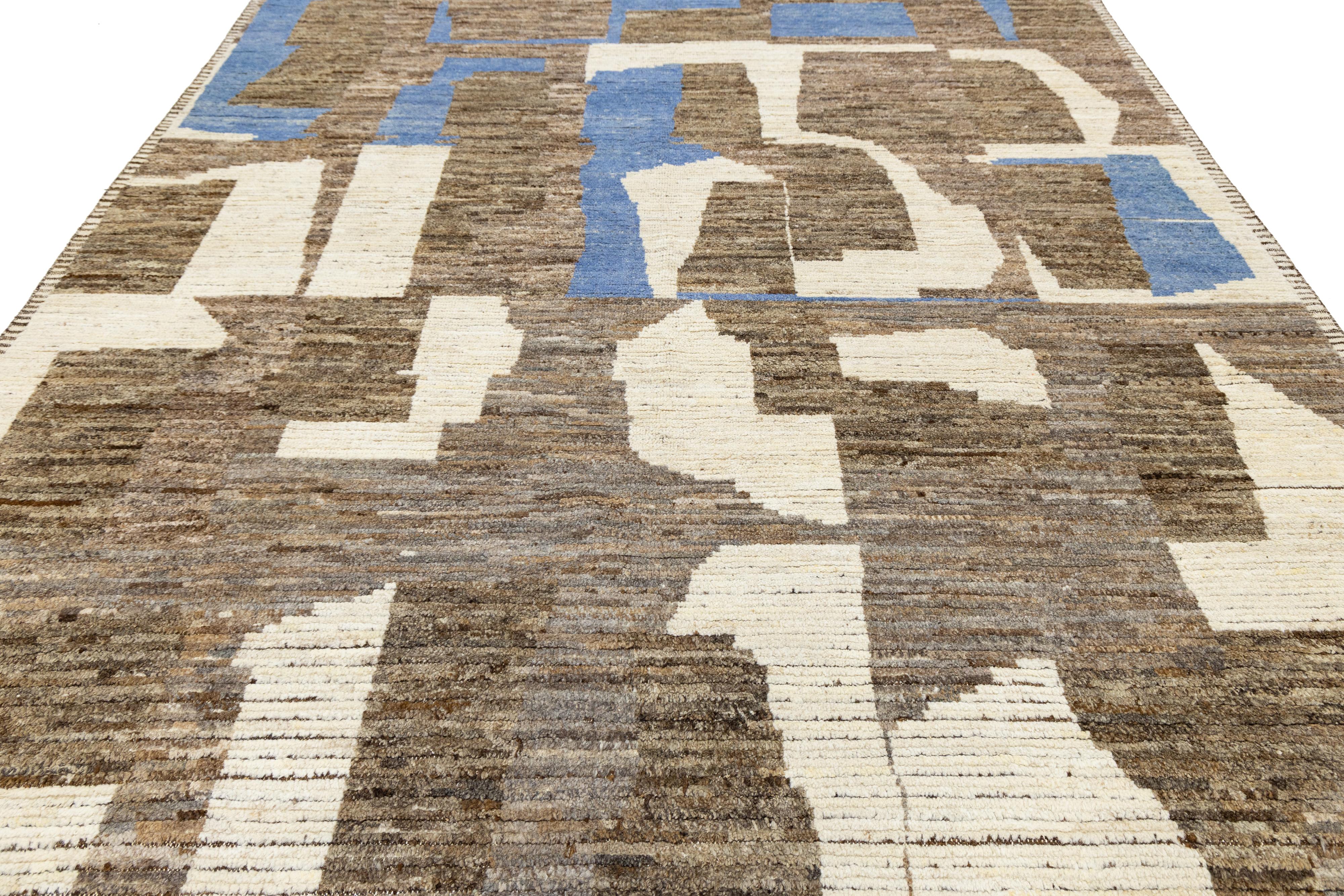 Handwoven in wool, this modern Moroccan-style rug features an abstract composition of earthy browns, off-white, and accents of blue. The irregular geometric blocks and horizontal texture evoke a painterly, contemporary aesthetic—ideal for curated