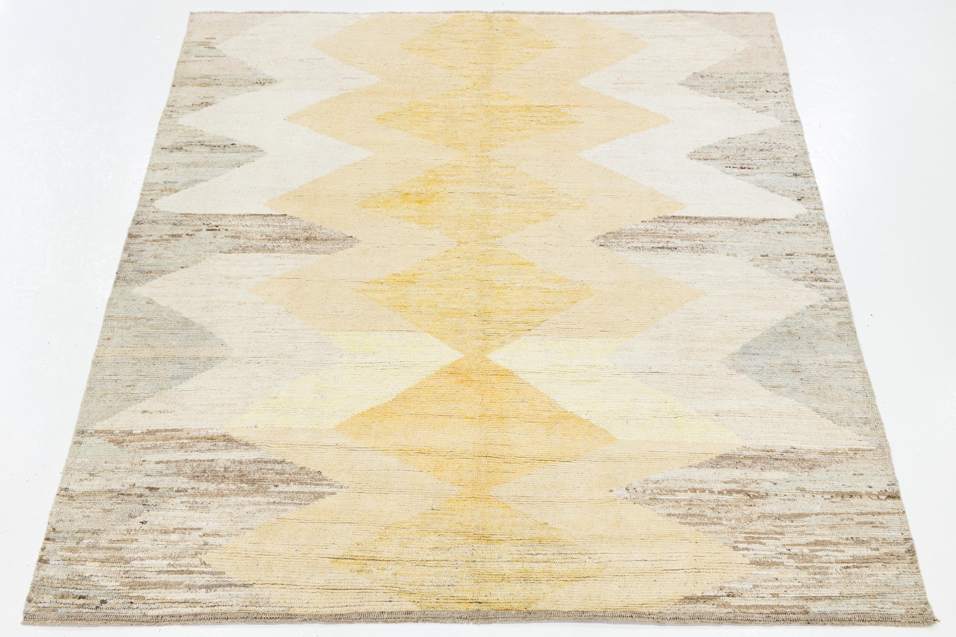 This handwoven modern Moroccan-style wool rug showcases a central diamond lattice flanked by zigzag borders in soft hues of yellow, taupe, and gray. The geometric symmetry and muted palette lend a refined, minimalist charm—perfect for contemporary,