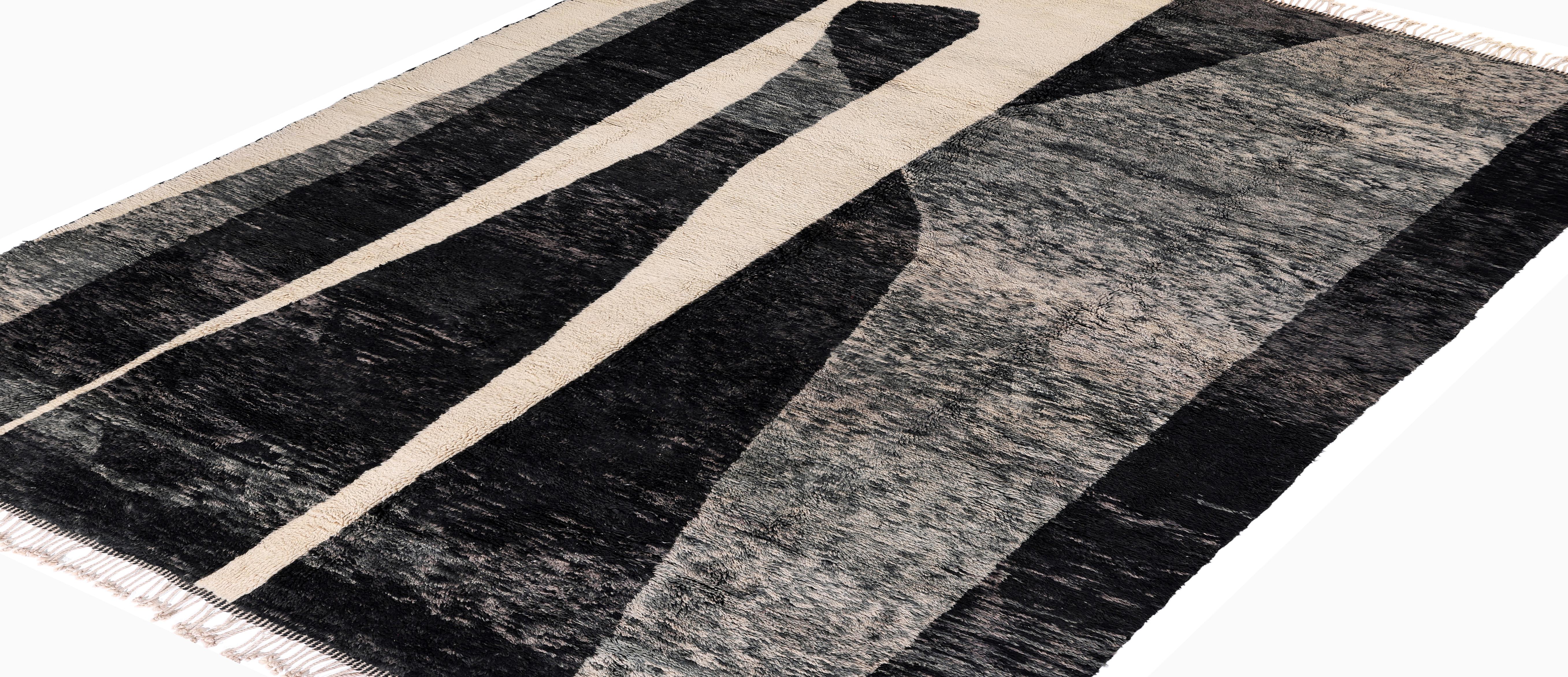 Aporta una atrevida sofisticación a tu interior con esta alfombra marroquí contemporánea de lana, magistralmente anudada a mano en suave lana de alta calidad. Con un espectacular diseño abstracto en ricos tonos negros y marfil cremoso, la alfombra
