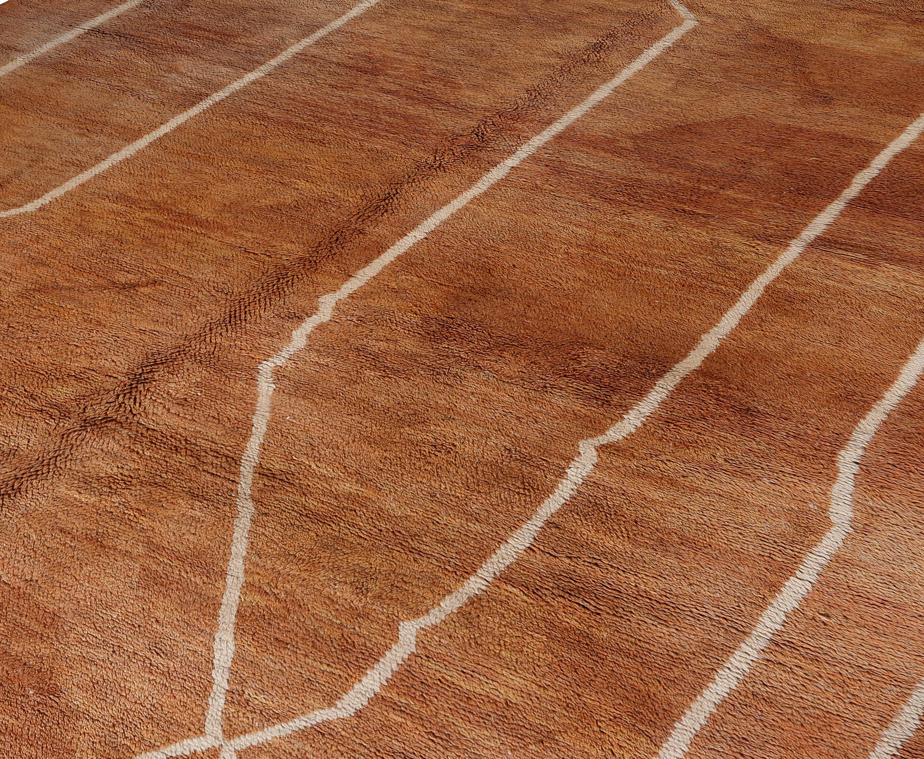 Rehaussez votre intérieur avec ce nouveau tapis marocain en laine, tissé à la main par des artisans qualifiés à l'aide de laine douce de première qualité. La riche base en terre cuite est rehaussée de lignes géométriques ivoire raffinées, créant un