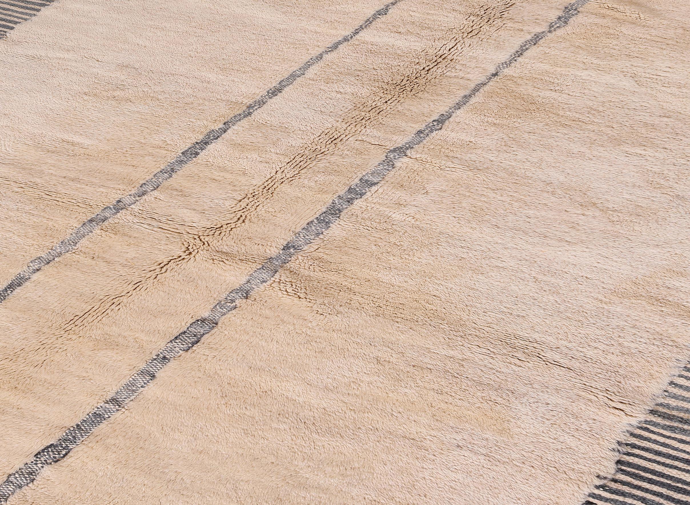 Handwoven in Morocco using 100% natural wool, this new Moroccan rug blends the timeless charm of tribal aesthetics with a clean, modern sensibility. Featuring a soft beige field framed by dark linear borders and vertical stripe accents, the rug