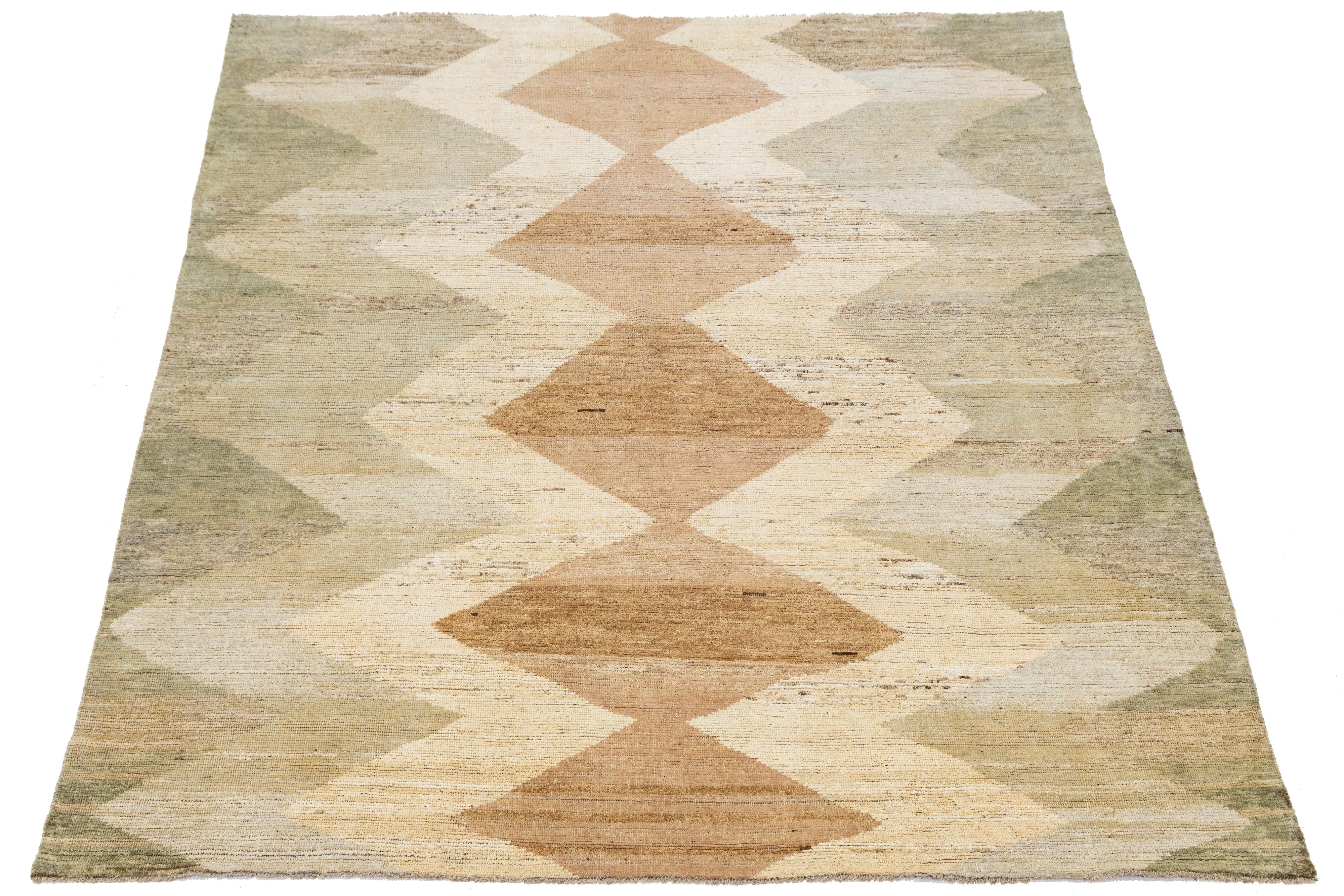 Flatwoven Moroccan-style wool rug showcasing earthy tones of beige, brown, and sage green. The bold central diamond pattern and zigzag accents evoke tribal symbolism with a minimalist edge. Handwoven texture and natural palette make it ideal for