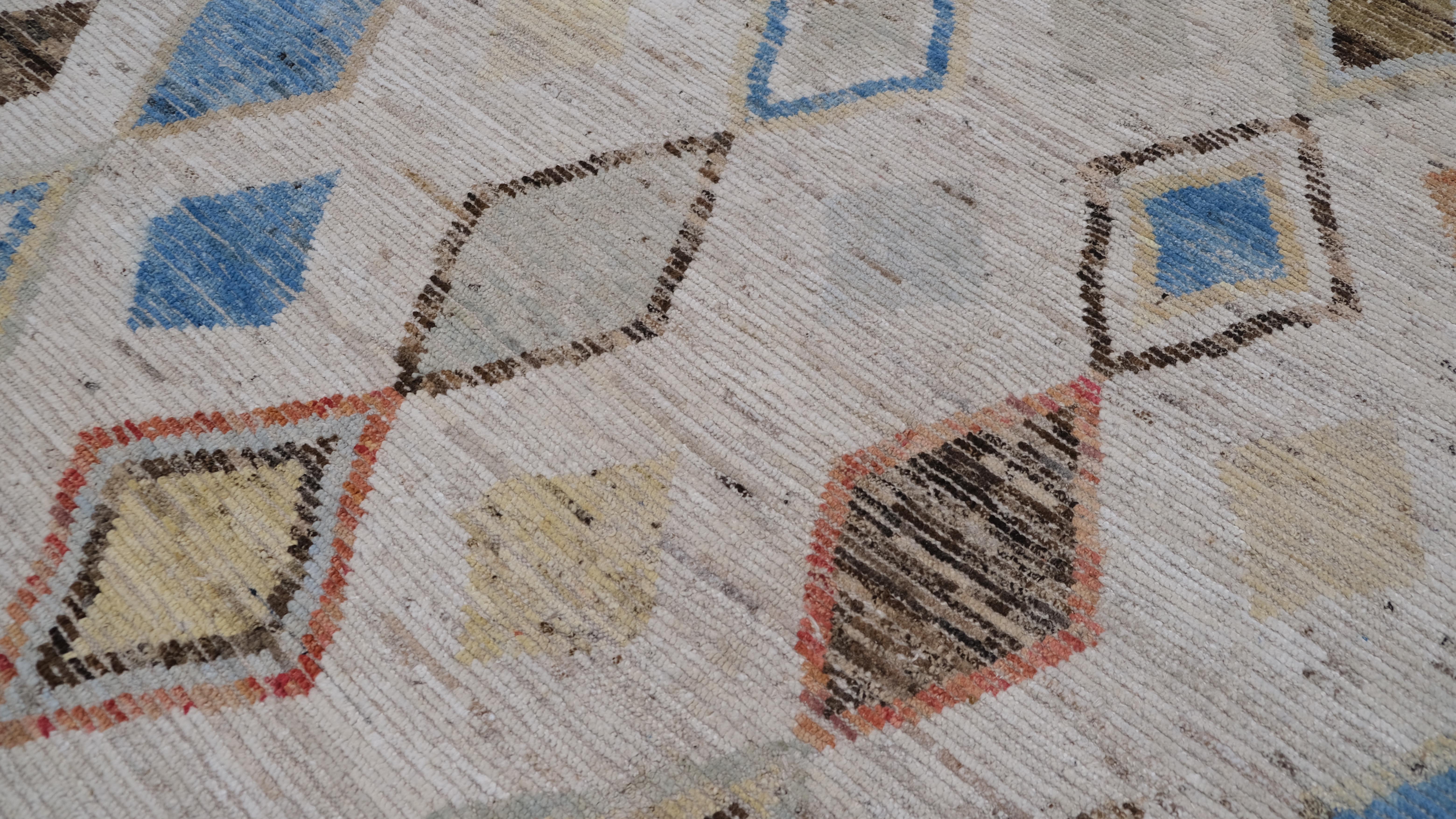 Dieser exquisite, handgeknüpfte Wollteppich besticht durch sein geometrisches Rautenmuster, das traditionelle Handwerkskunst mit moderner Ästhetik verbindet. Mit einer Reihe von mehrfarbigen Diamanten in Blau-, Rot-, Orange-, Gelb- und Brauntönen